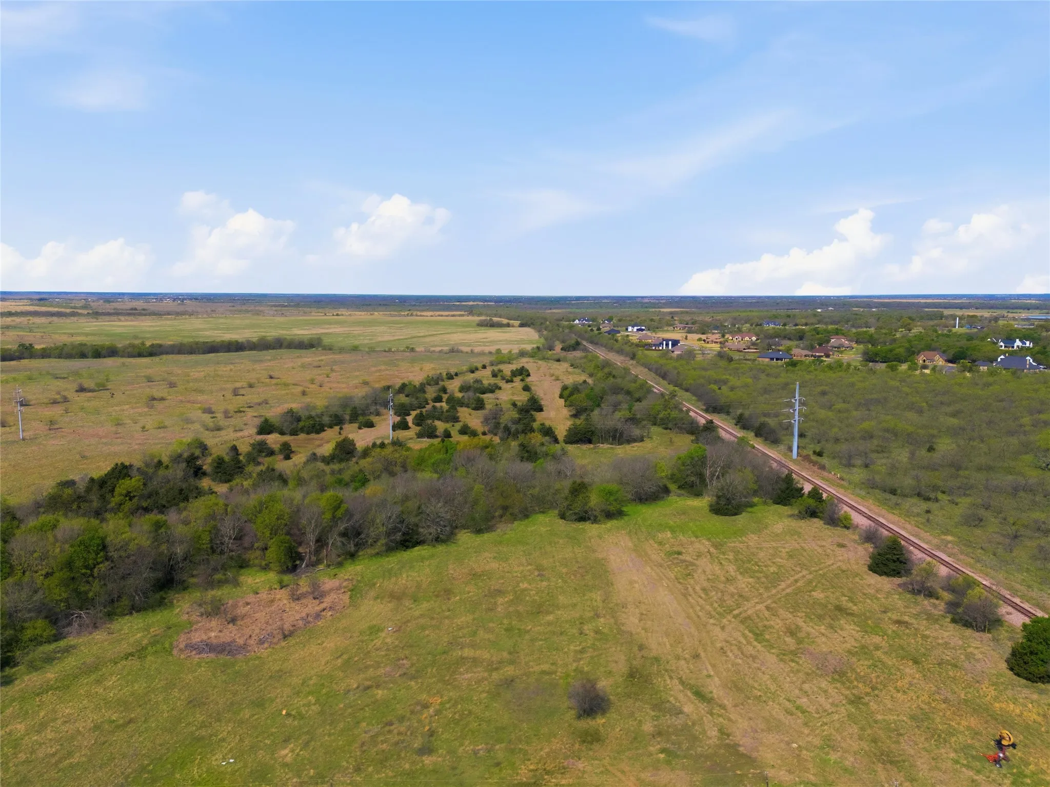 Expansive land parcel featuring natural vegetation, open grassy areas, and a visible railway line