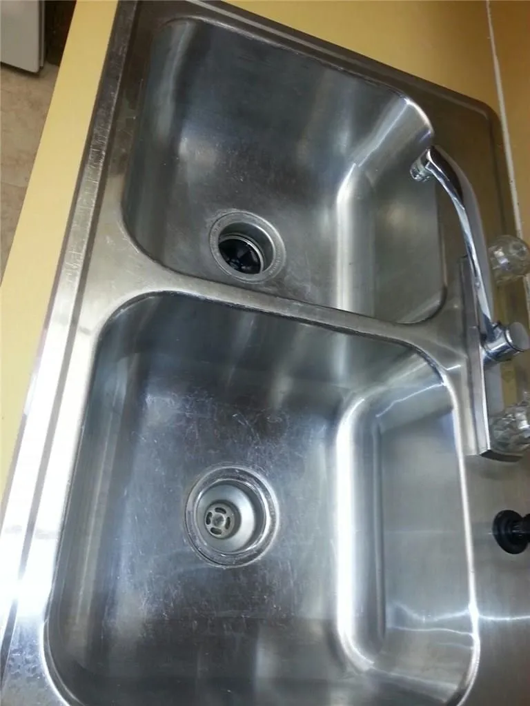 Dual basin stainless steel kitchen sink with a chrome faucet