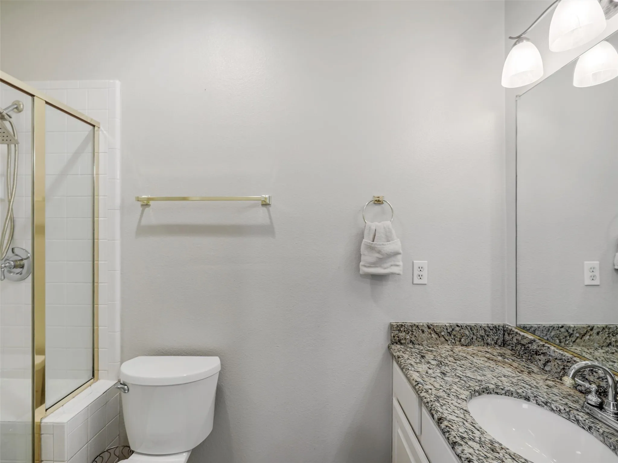 Shower with gold-toned enclosure and white subway tile surround