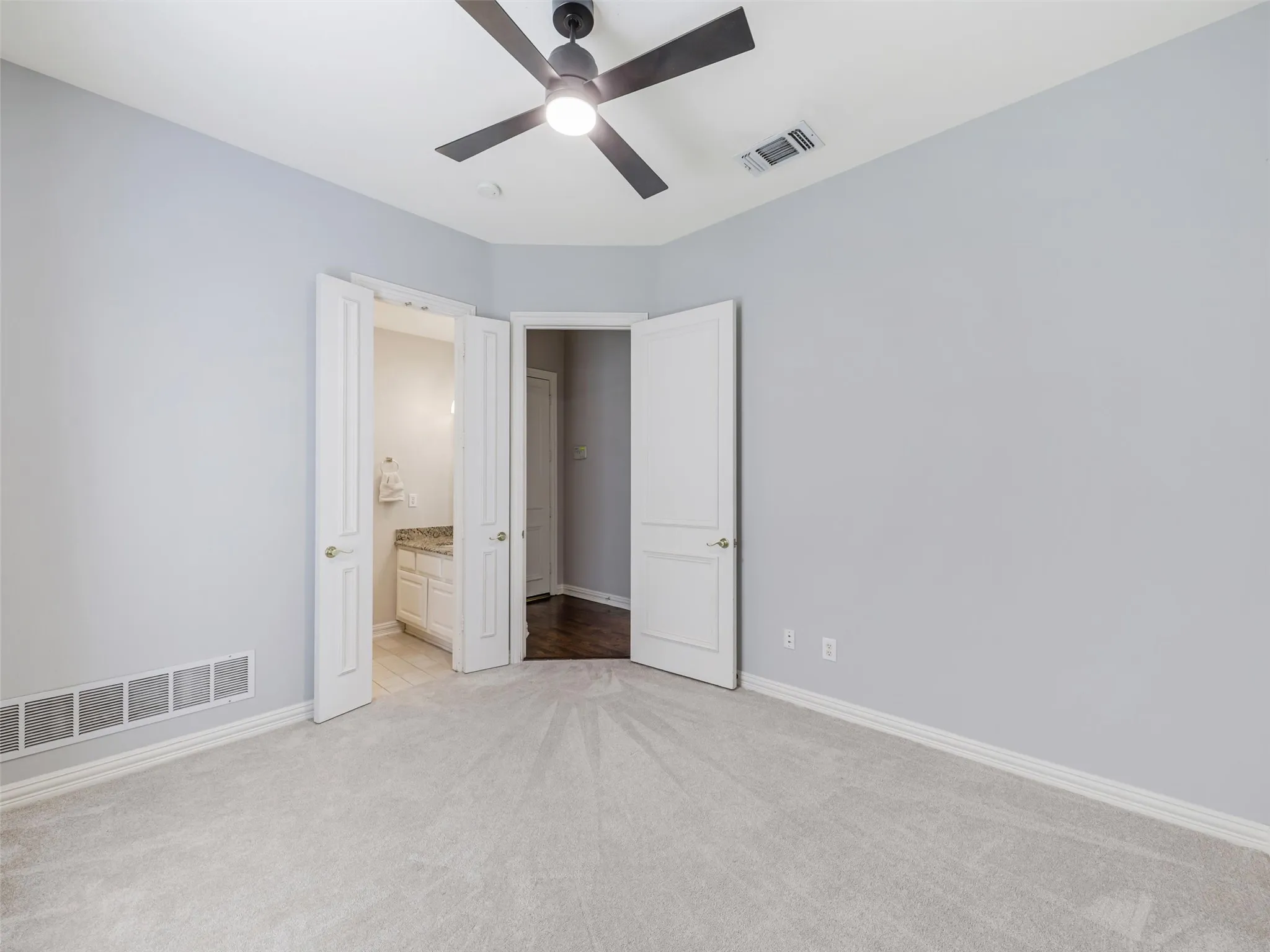 Expansive carpeting with light-toned walls and a ceiling fan