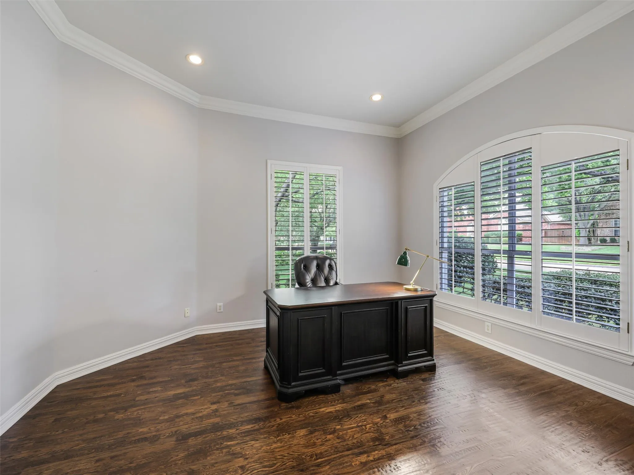 Wood-finish flooring, recessed lighting, crown molding, arched window, and plantation shutters