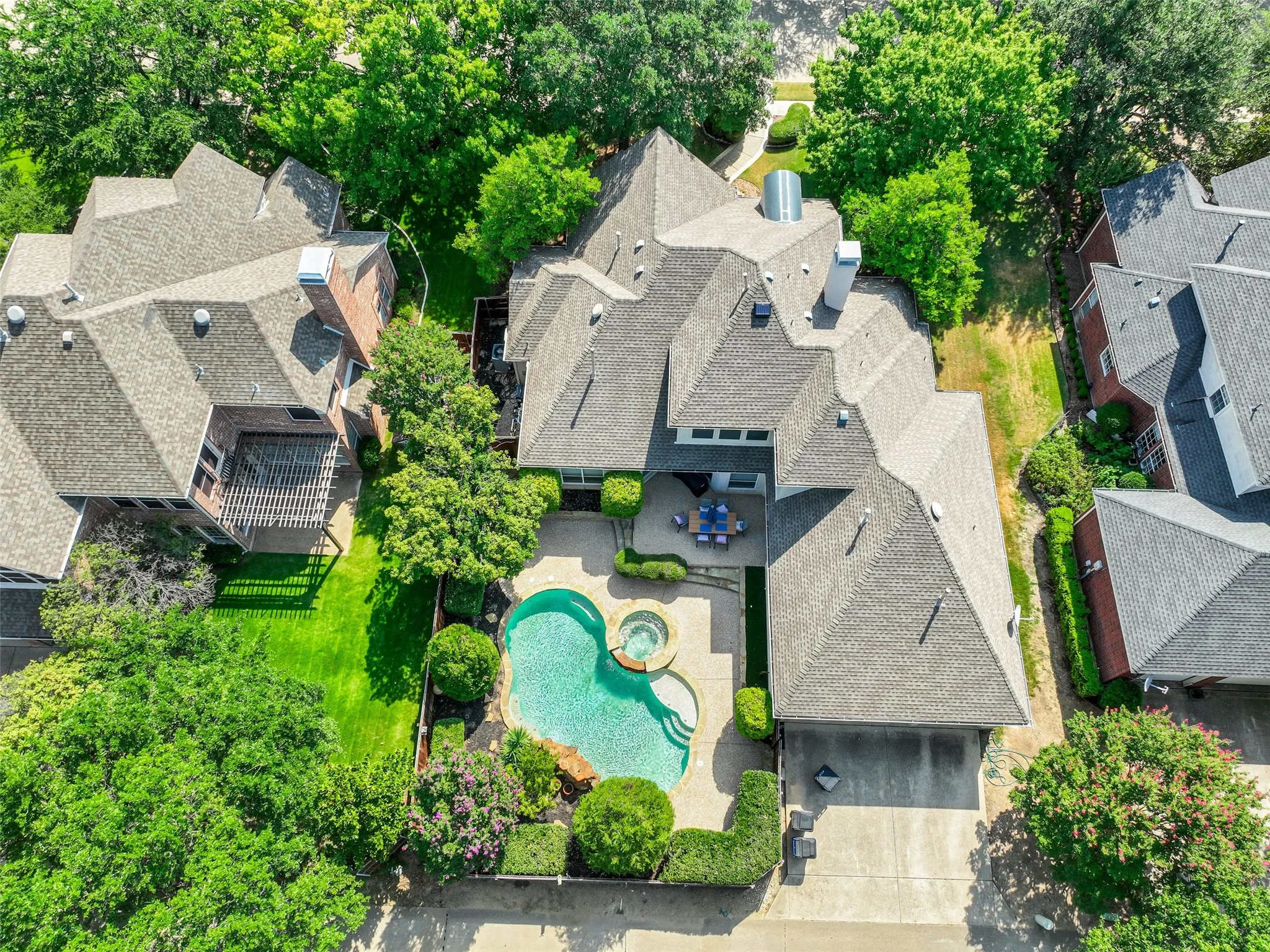 Rear exterior featuring a freeform swimming pool with integrated spa, stone coping, and a paver patio