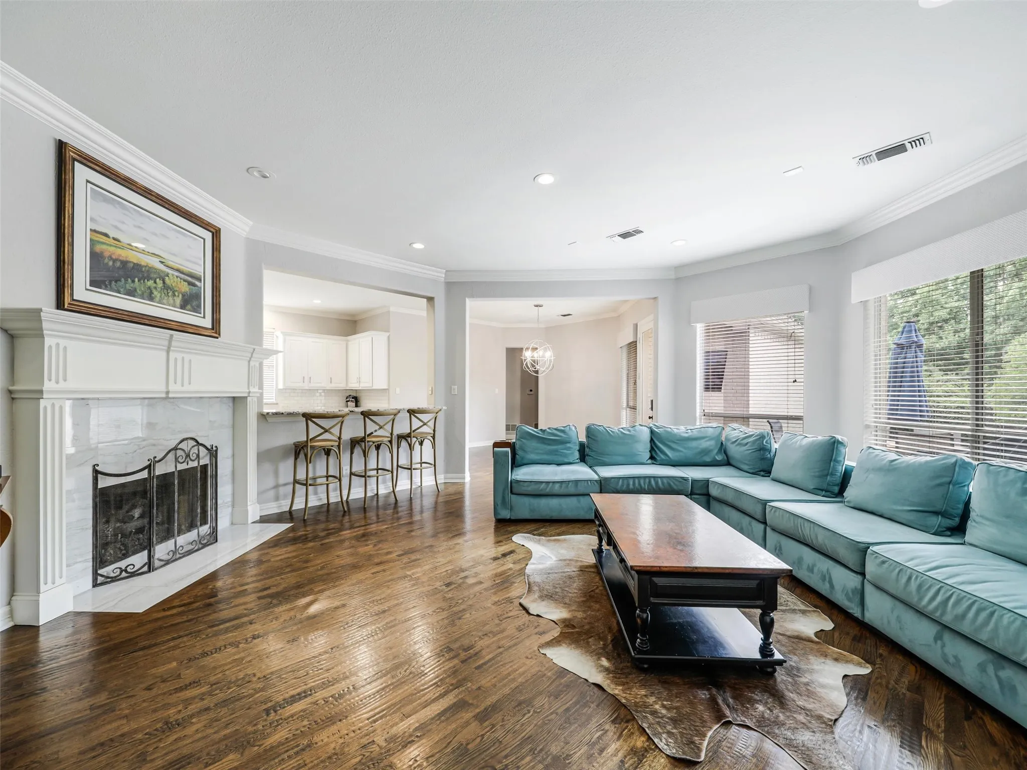 Hardwood flooring, crown molding, a built-in fireplace with a stone surround, recessed lighting, and large windows