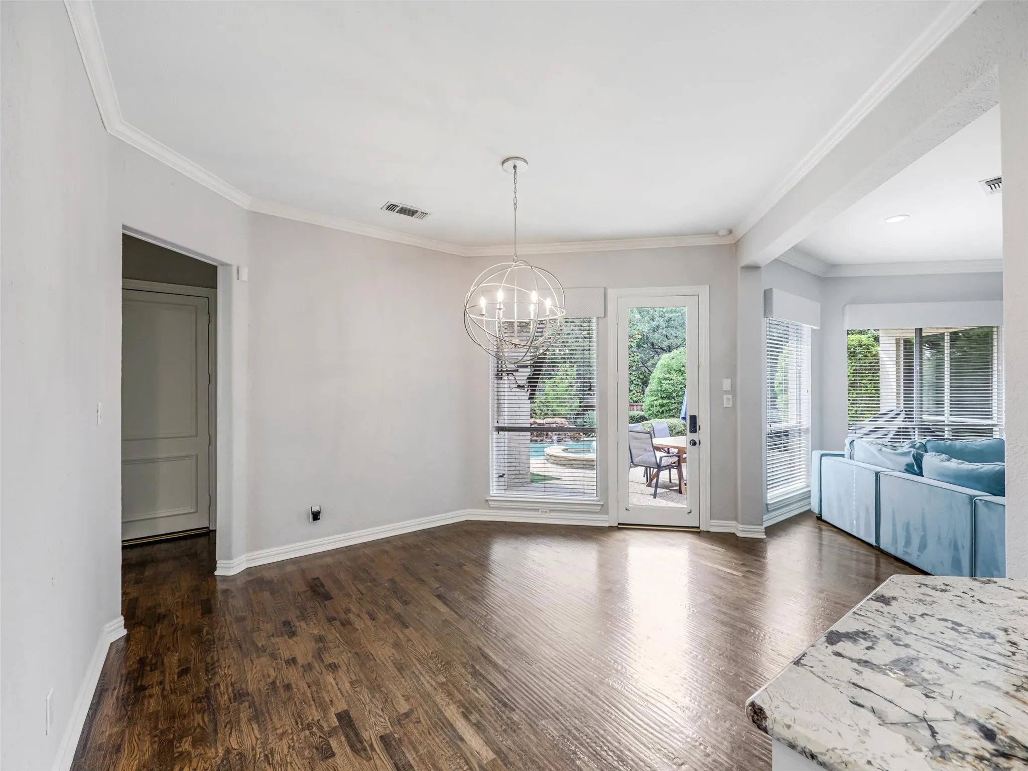 Hardwood flooring, crown molding, modern chandelier, full-light door to exterior, and bay windows