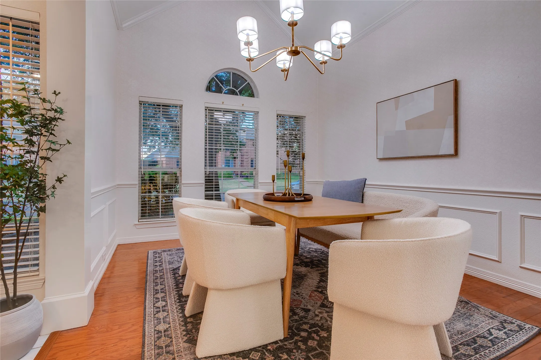 Classic elements create an upscale space for formal dining. Crown molding at the ceiling, picture molding below the chair rail with papered walls above and a Palladian window accentuate the room.