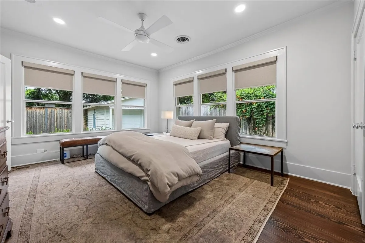 Bright room featuring multiple windows with roller shades, recessed lighting, a ceiling fan, crown molding, and dark wood-finish flooring