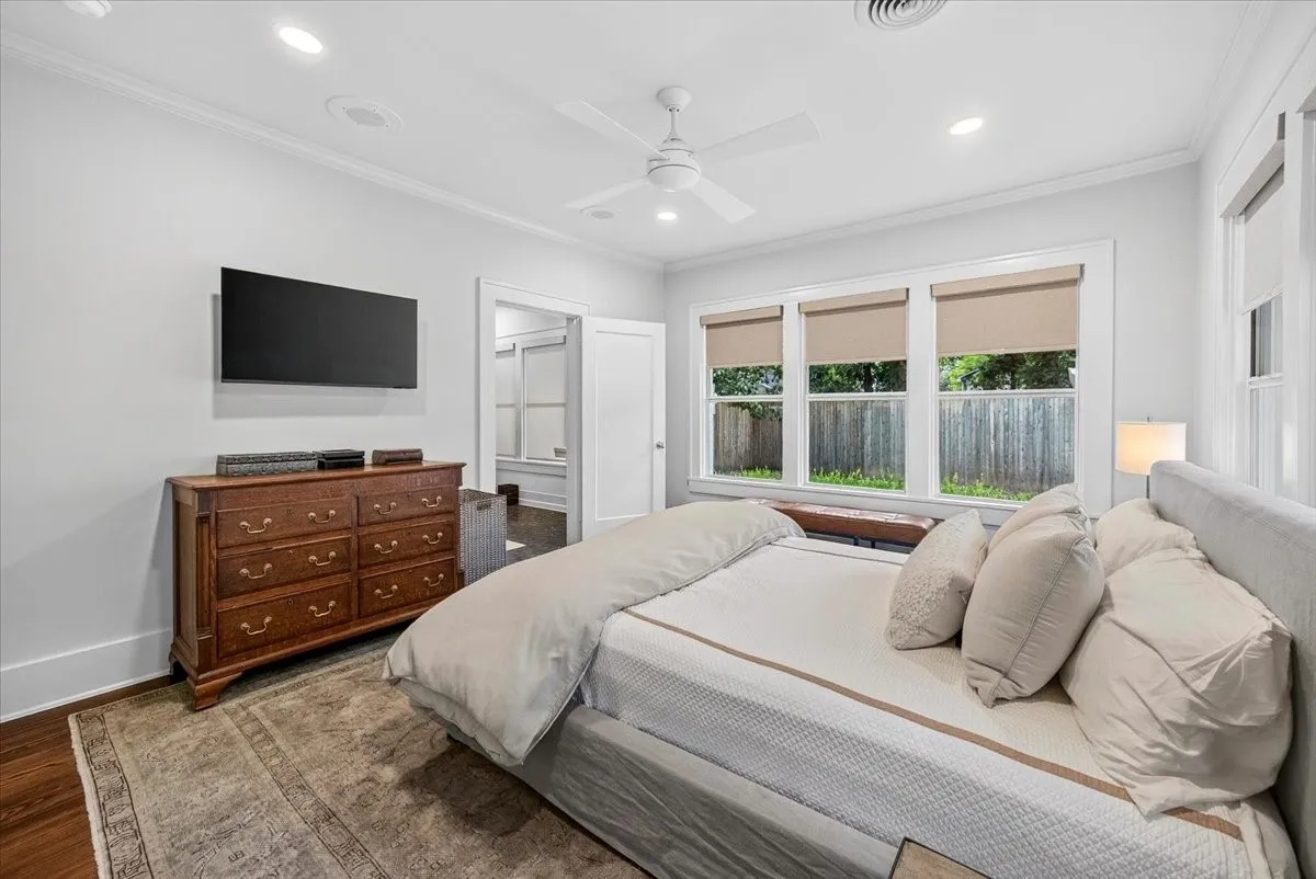 Bright room featuring multiple windows with roller shades, recessed lighting, crown molding, and wood-finish flooring