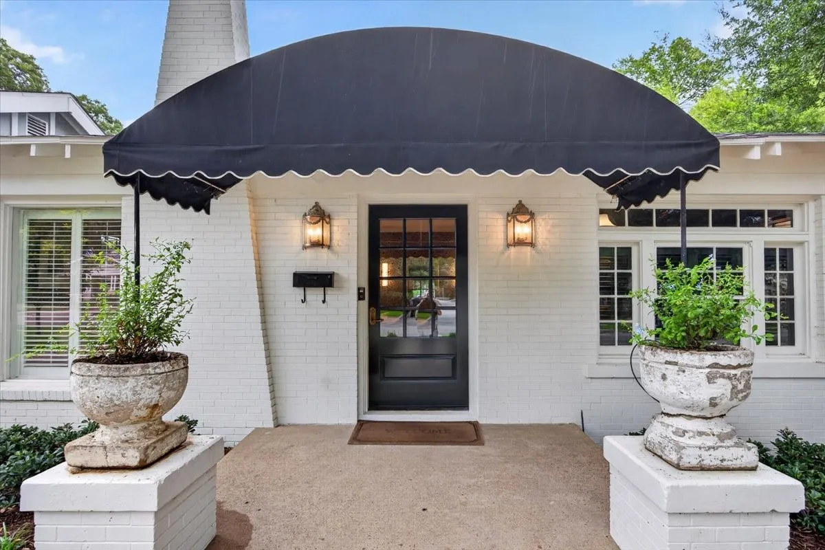 White brick facade featuring a black arched awning with scalloped trim