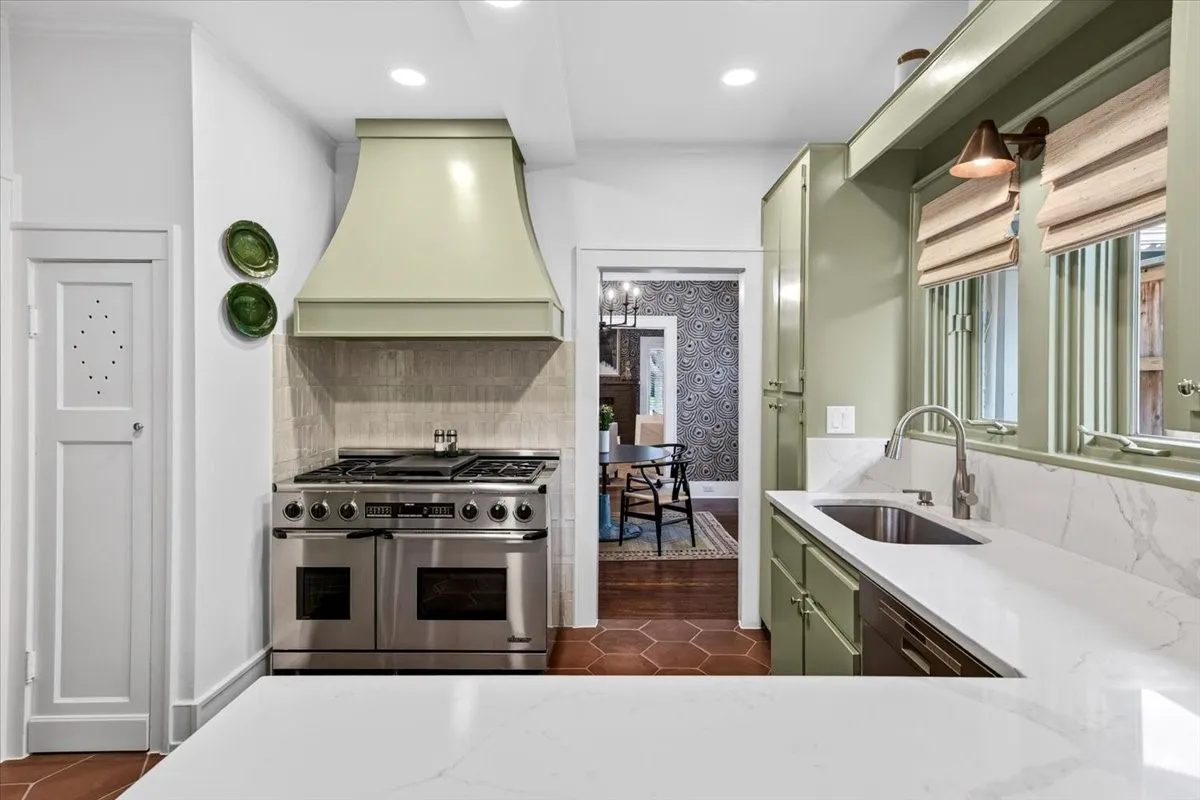 Kitchen featuring a professional-grade stainless steel range, custom sage green cabinetry, white stone countertops, and hexagonal terracotta tile flooring