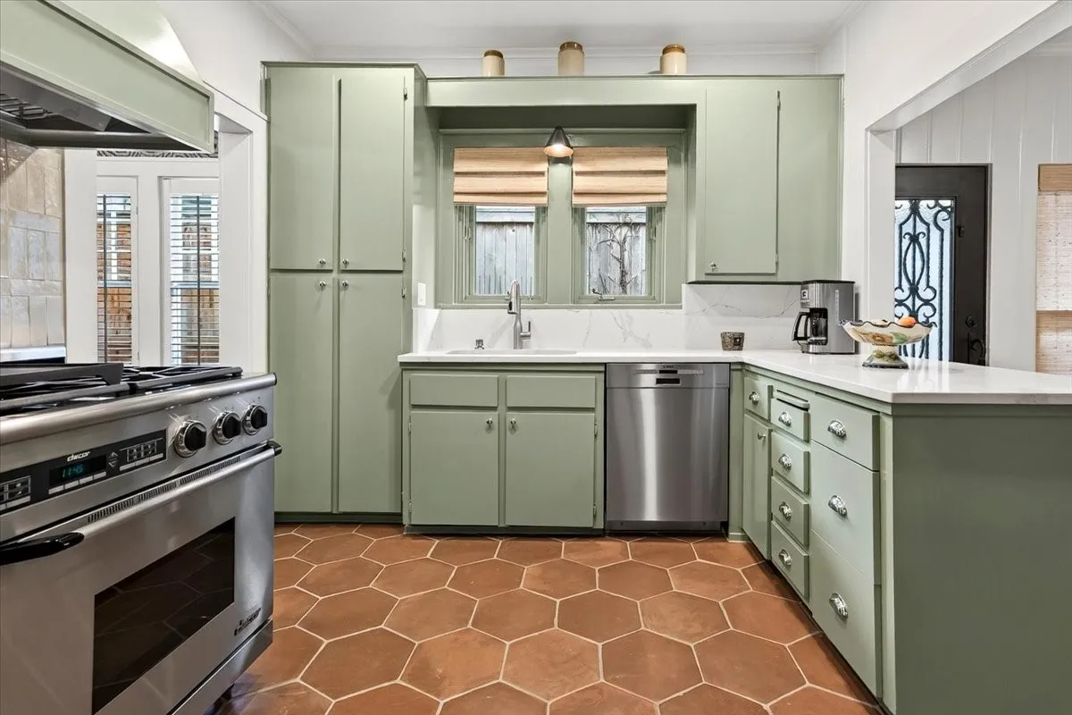 Kitchen featuring sage green cabinetry, stainless steel appliances, white countertops, and hexagonal terra cotta tile flooring