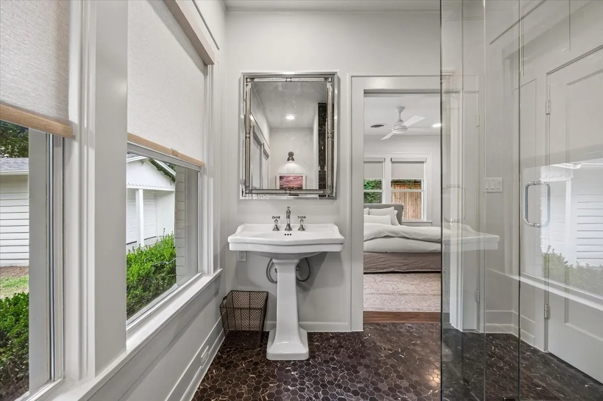 Pedestal sink with a framed mirror, hexagon tile flooring, and a clear glass shower enclosure