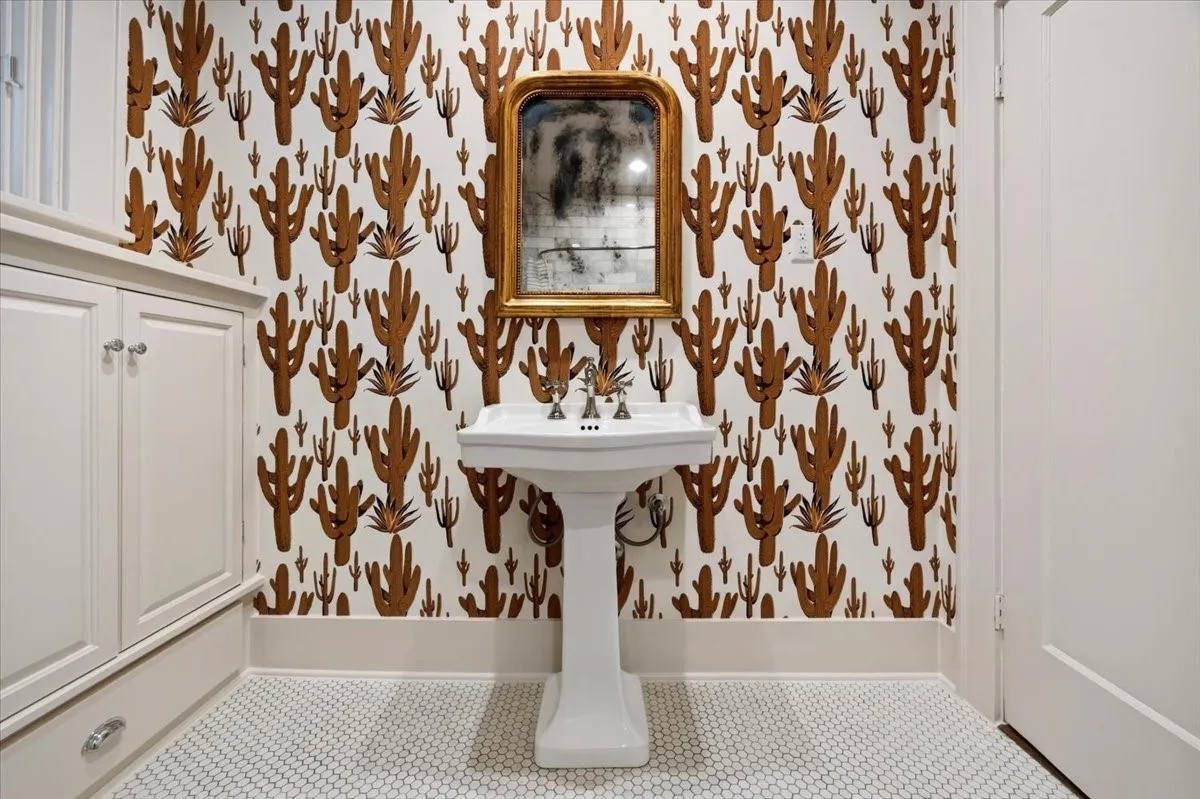 Pedestal sink with polished chrome fixtures, set against a cactus-patterned wall covering