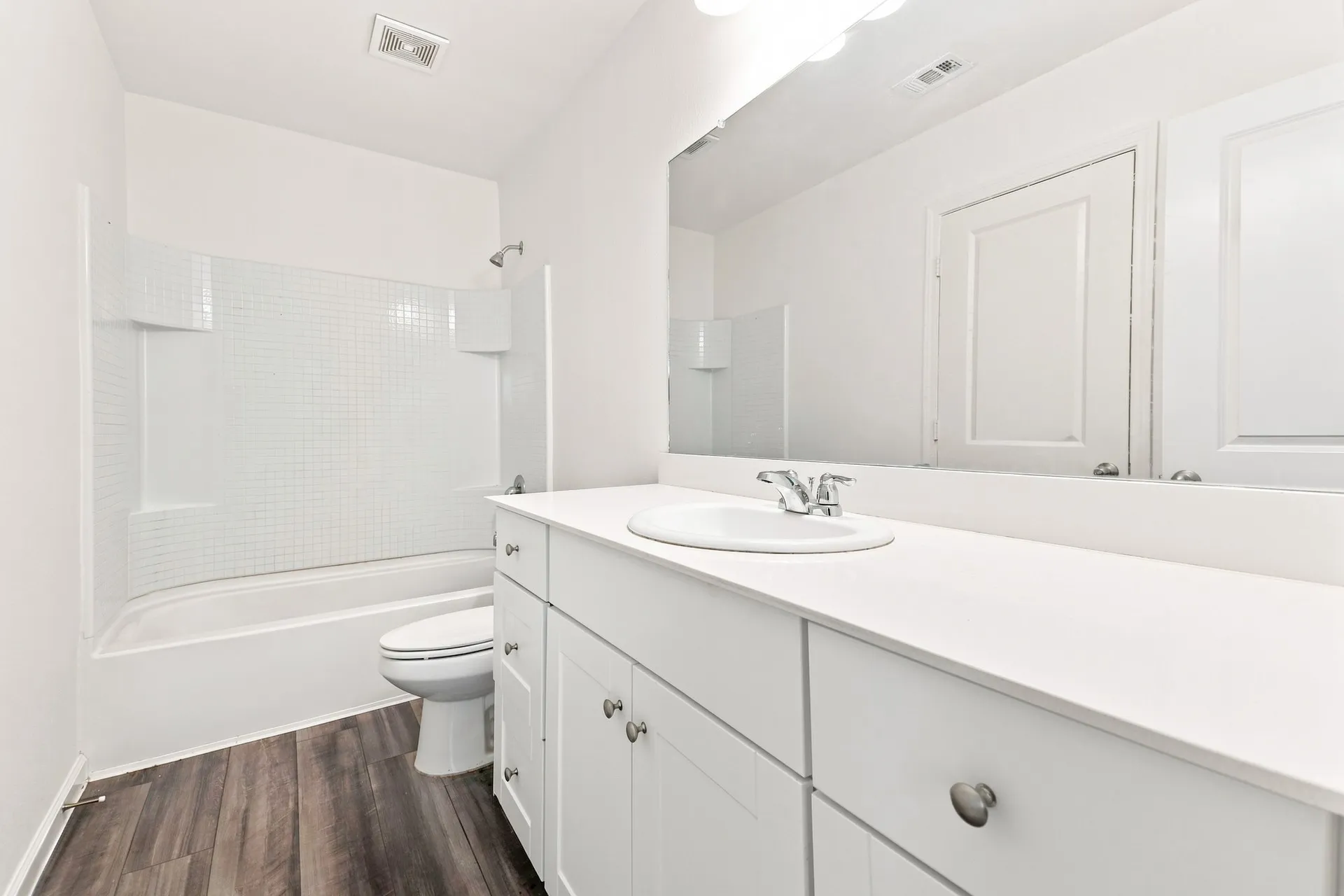 Bathroom featuring a white vanity with integrated sink, white countertop, and wood-finish flooring