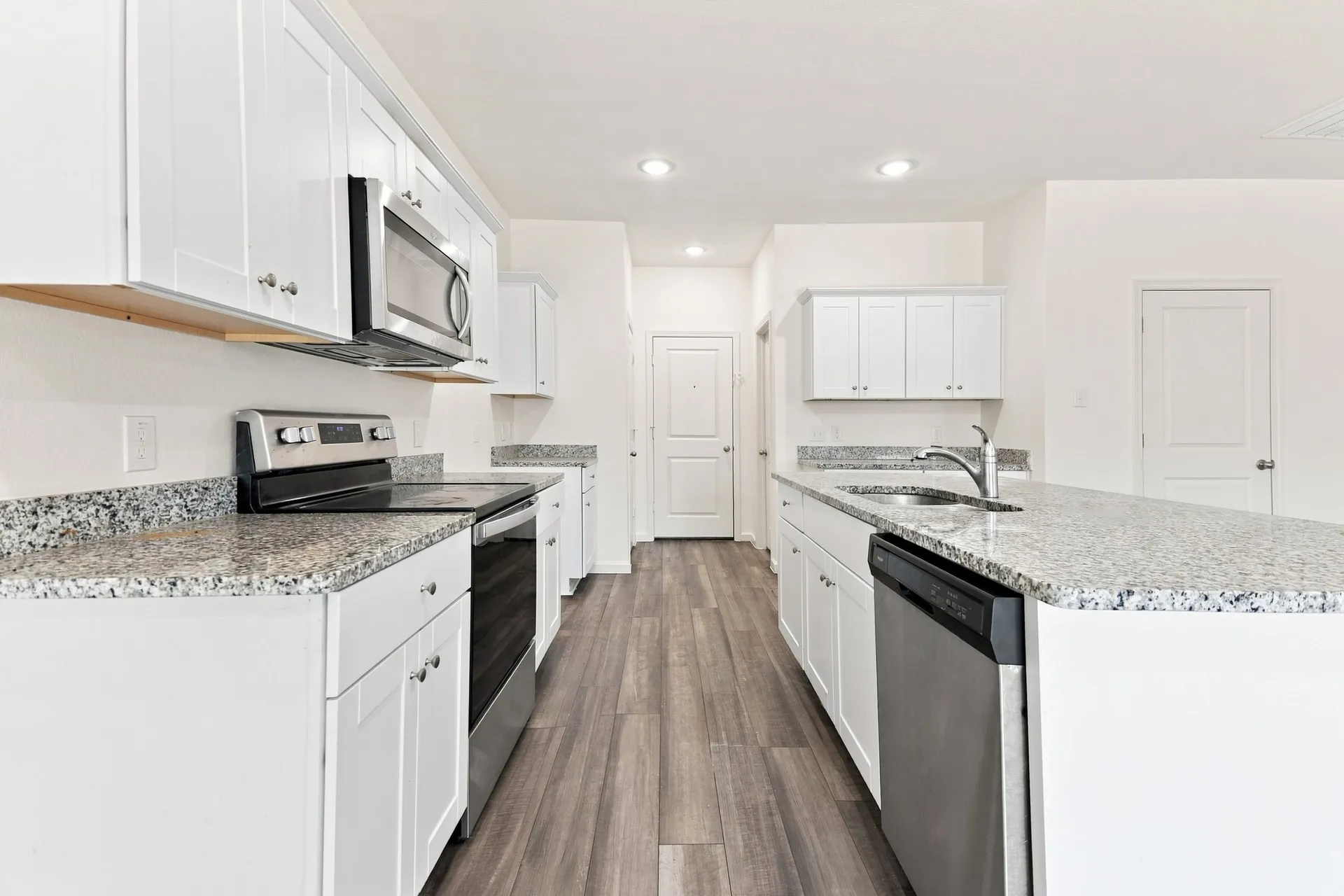 Contemporary kitchen featuring white cabinetry and granite countertops