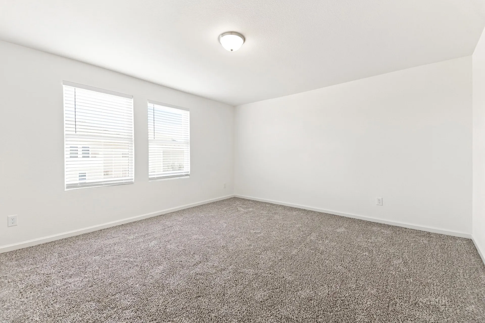 Spacious room featuring neutral carpeting and white painted walls