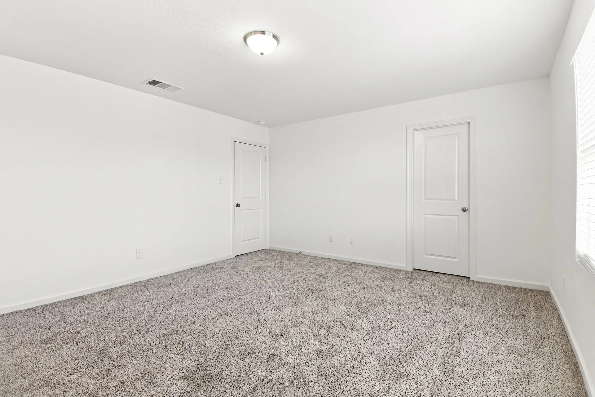 Spacious room featuring neutral carpeting, white painted walls, and white trim