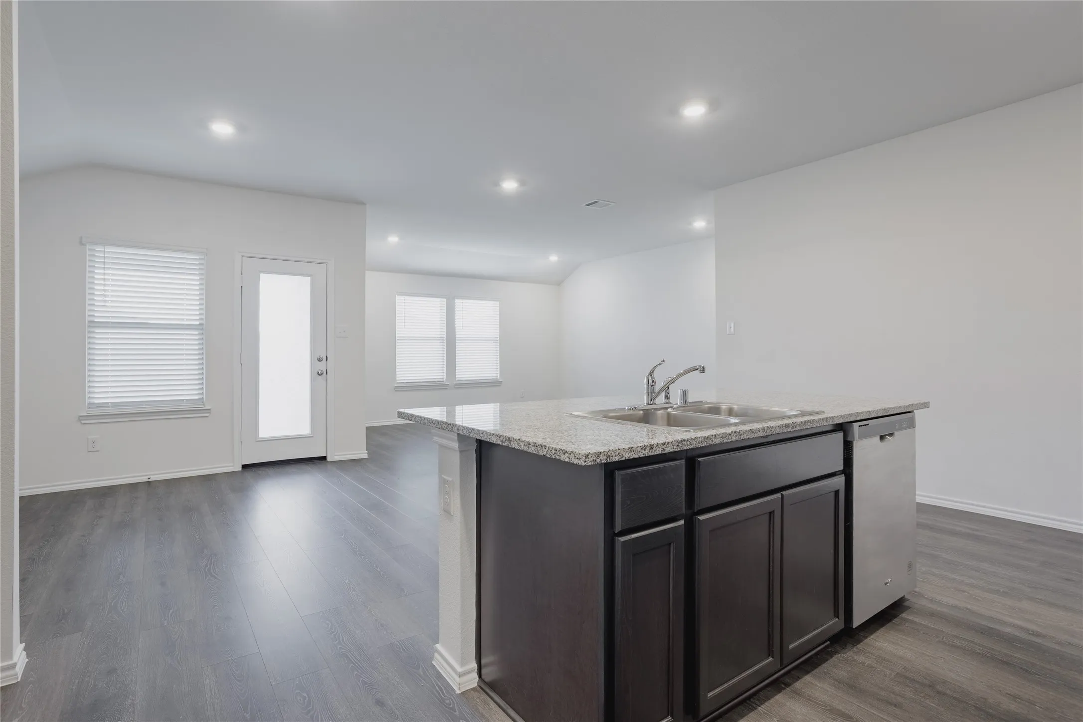 Kitchen island featuring a double-basin stainless steel sink, granite-style countertop, and integrated dishwasher