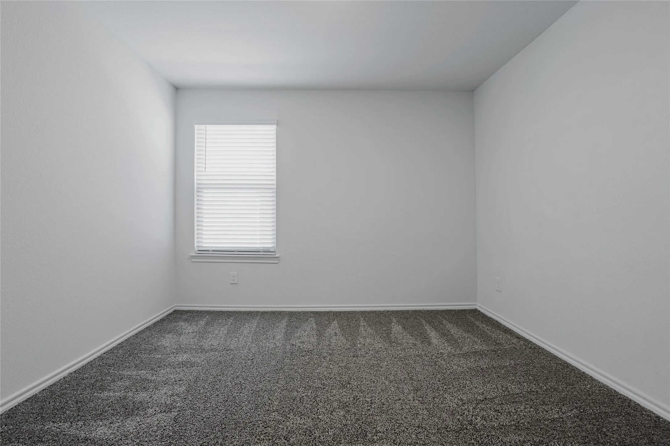 Room featuring white walls and grey patterned carpeting