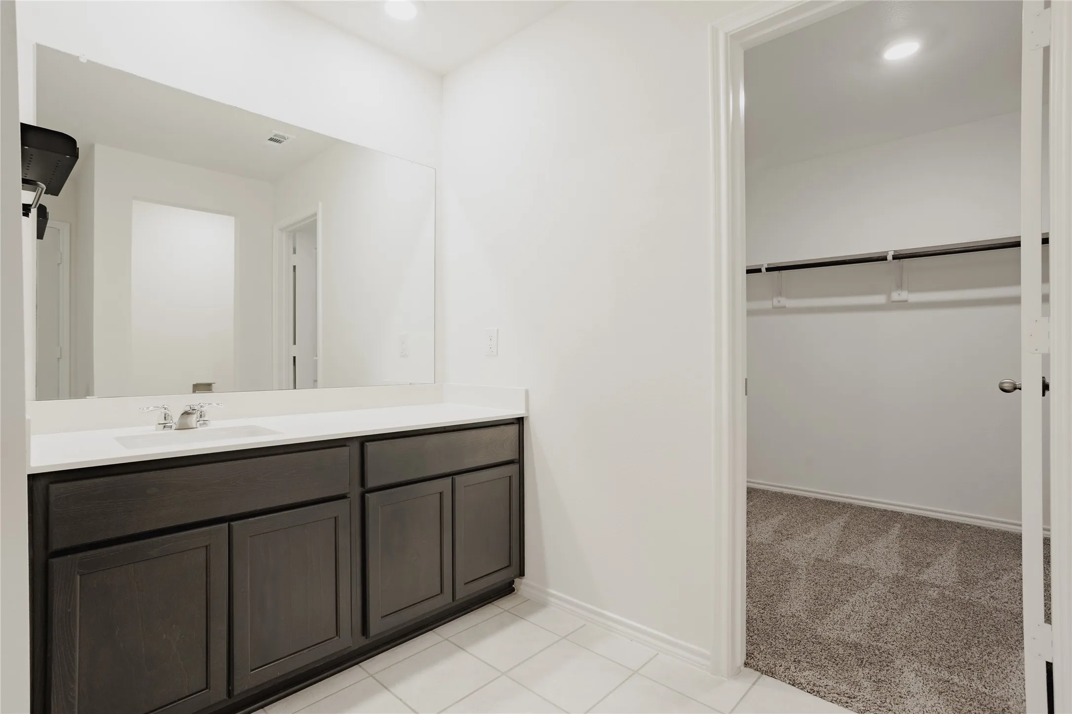 Bathroom vanity with a white countertop and dark wood-finish cabinetry
