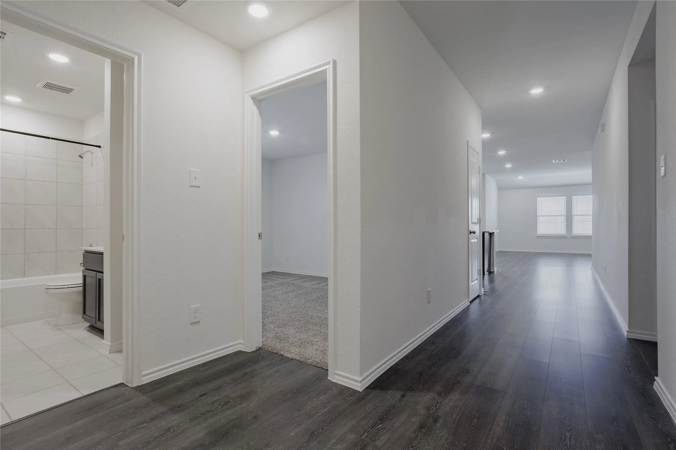 Hallway with dark wood-finish flooring, recessed lighting, and white baseboards