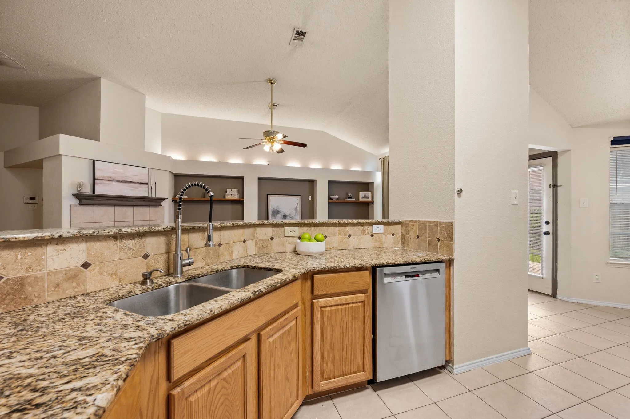 Kitchen featuring granite countertops, wood cabinetry, a double basin stainless steel sink, and a stainless steel dishwasher