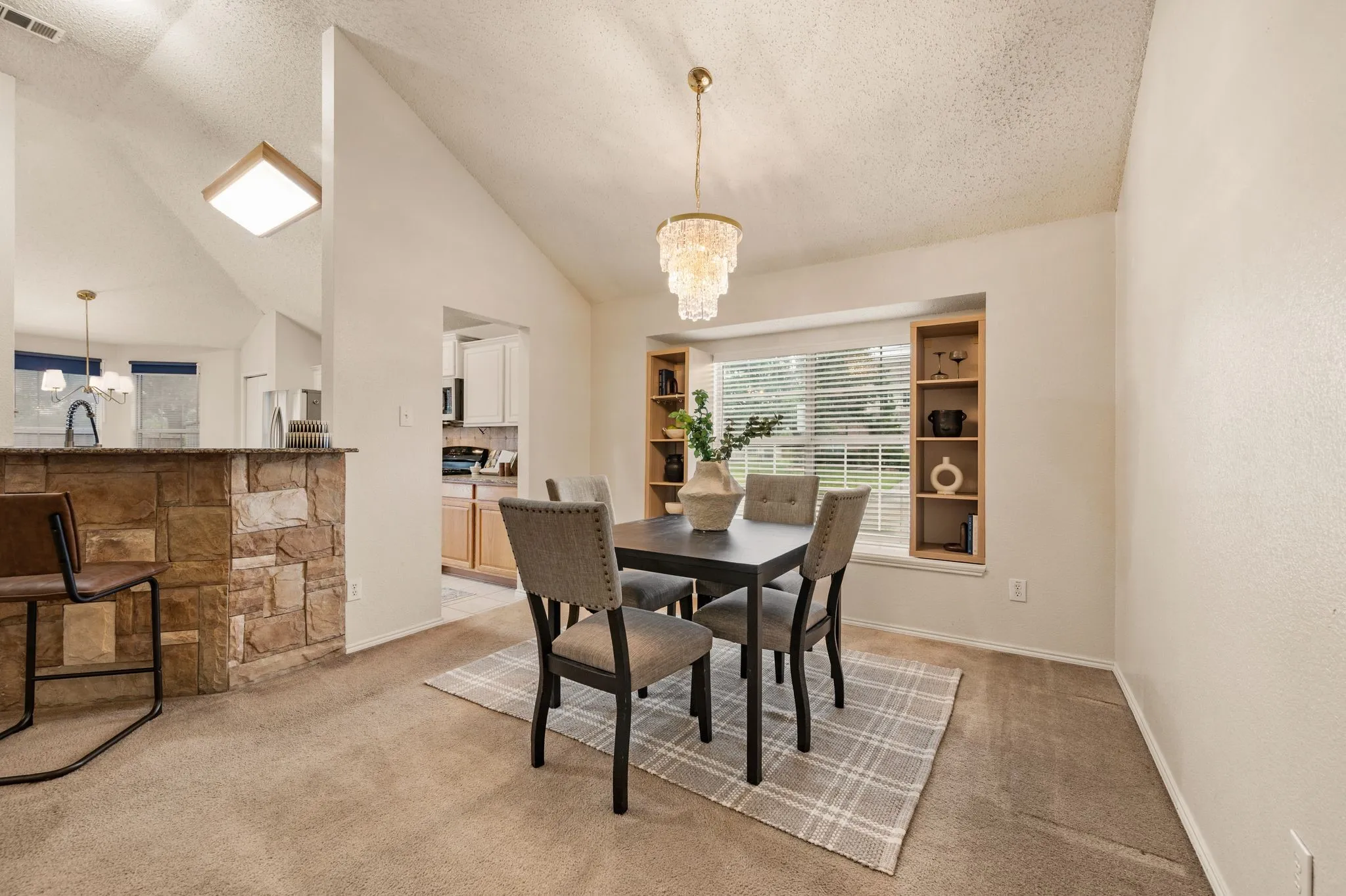 Dining area featuring vaulted ceilings, a tiered chandelier, built-in shelving, and a large window