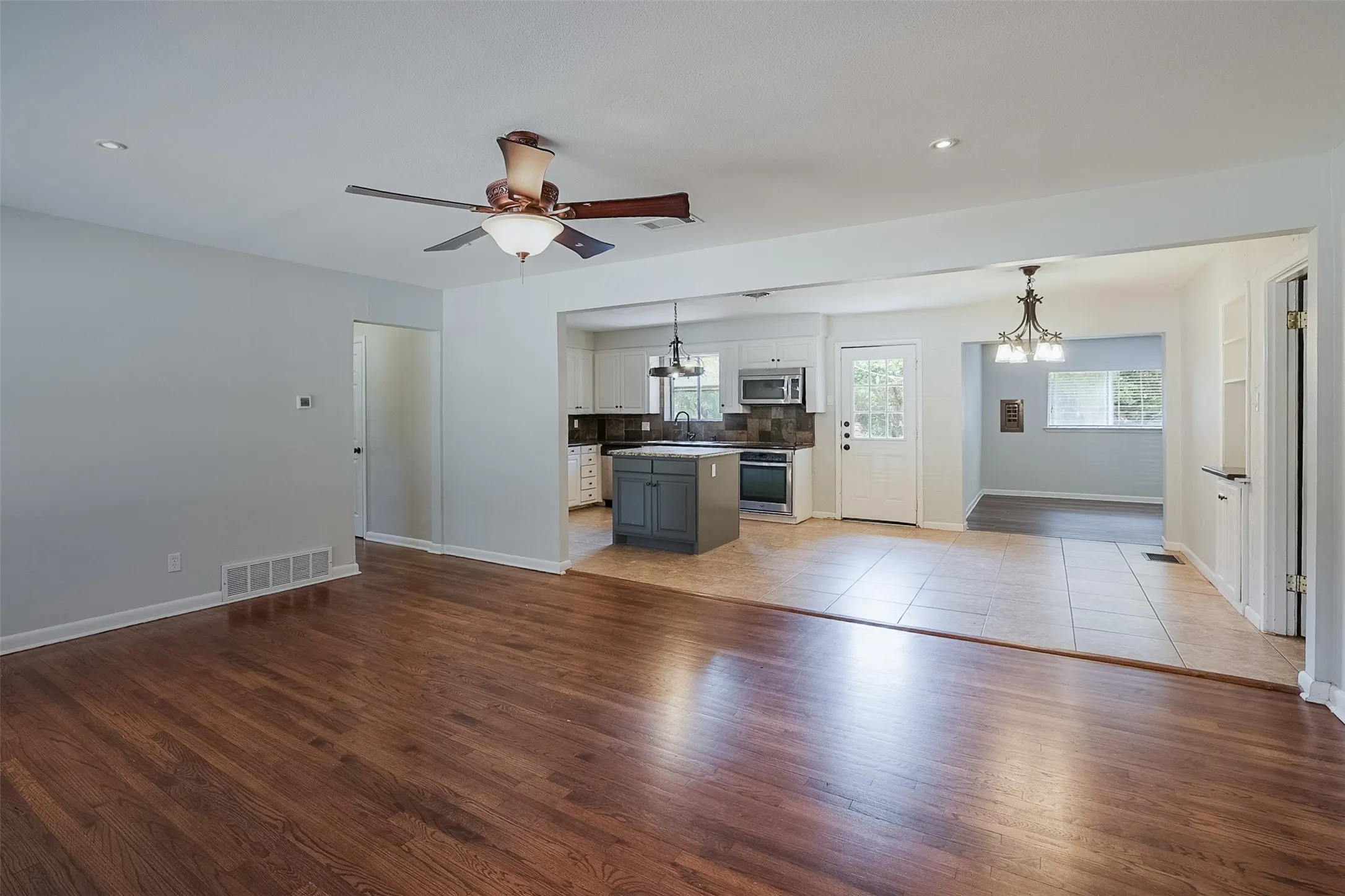 Hardwood flooring, ceiling fan with integrated lighting, recessed lighting, tile flooring, and a kitchen island with built-in cabinetry