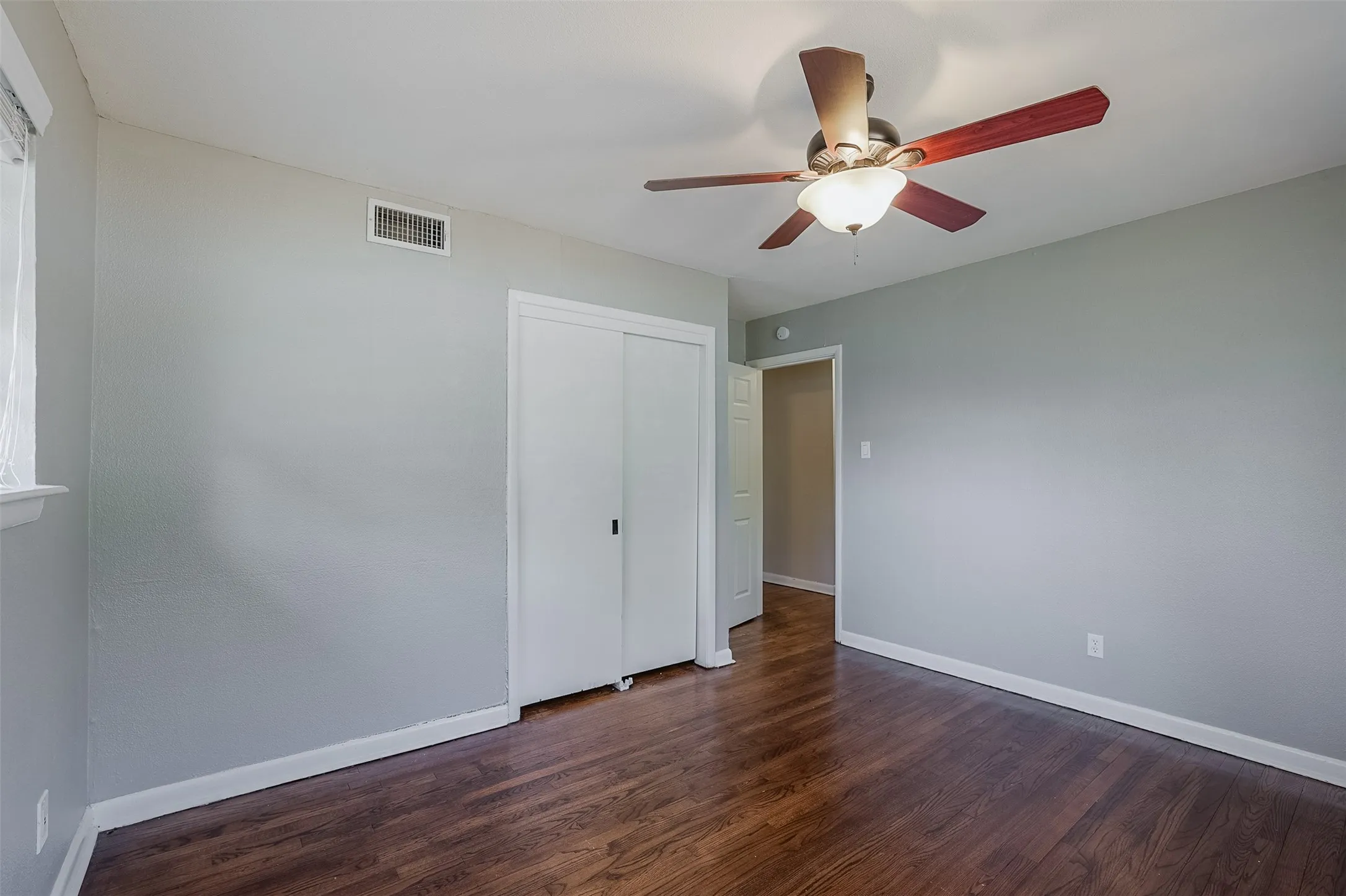 Wood-finish flooring, ceiling fan with integrated lighting, sliding closet doors, and recessed lighting
