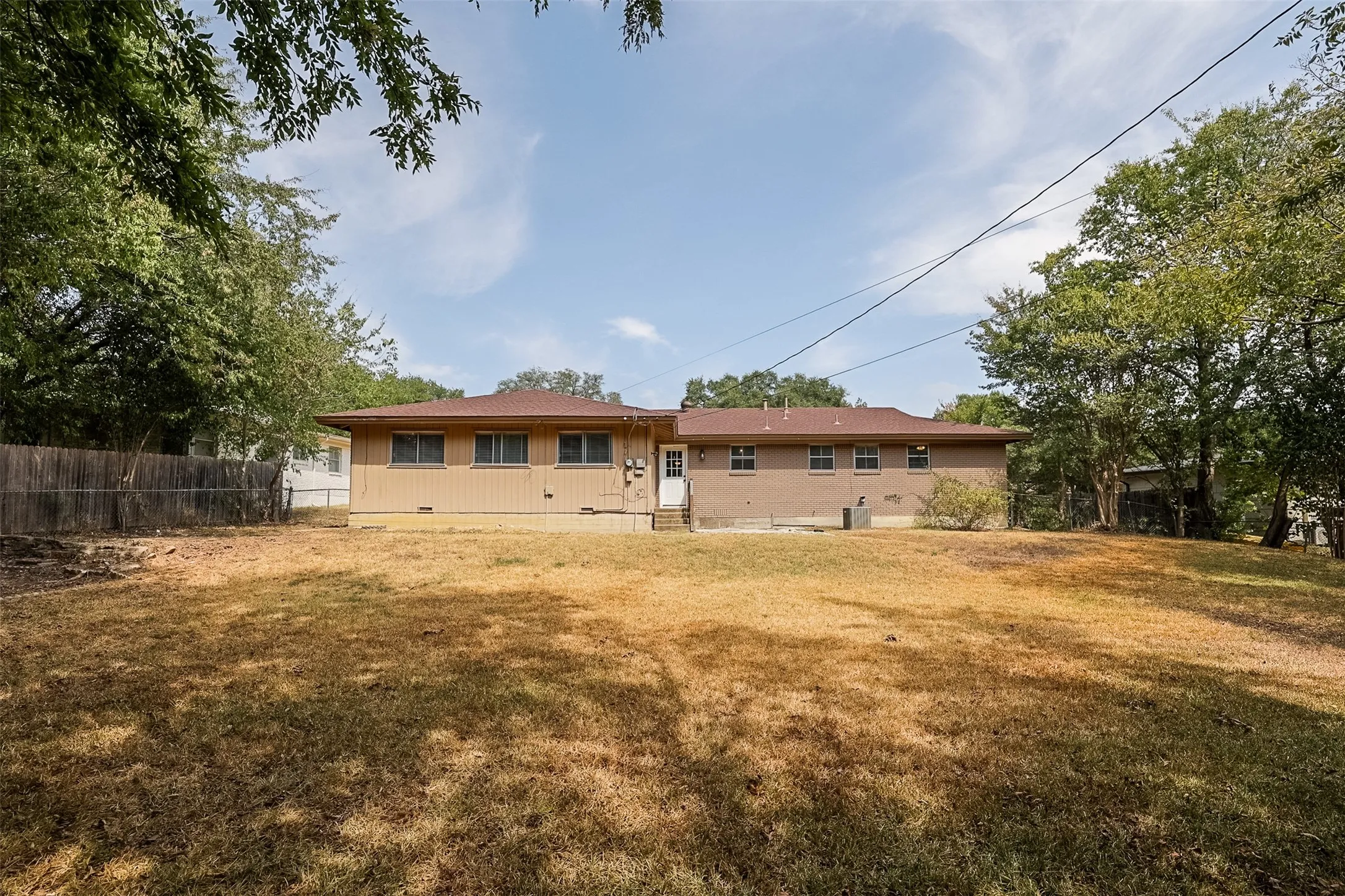 Expansive rear yard with mature trees and perimeter fencing