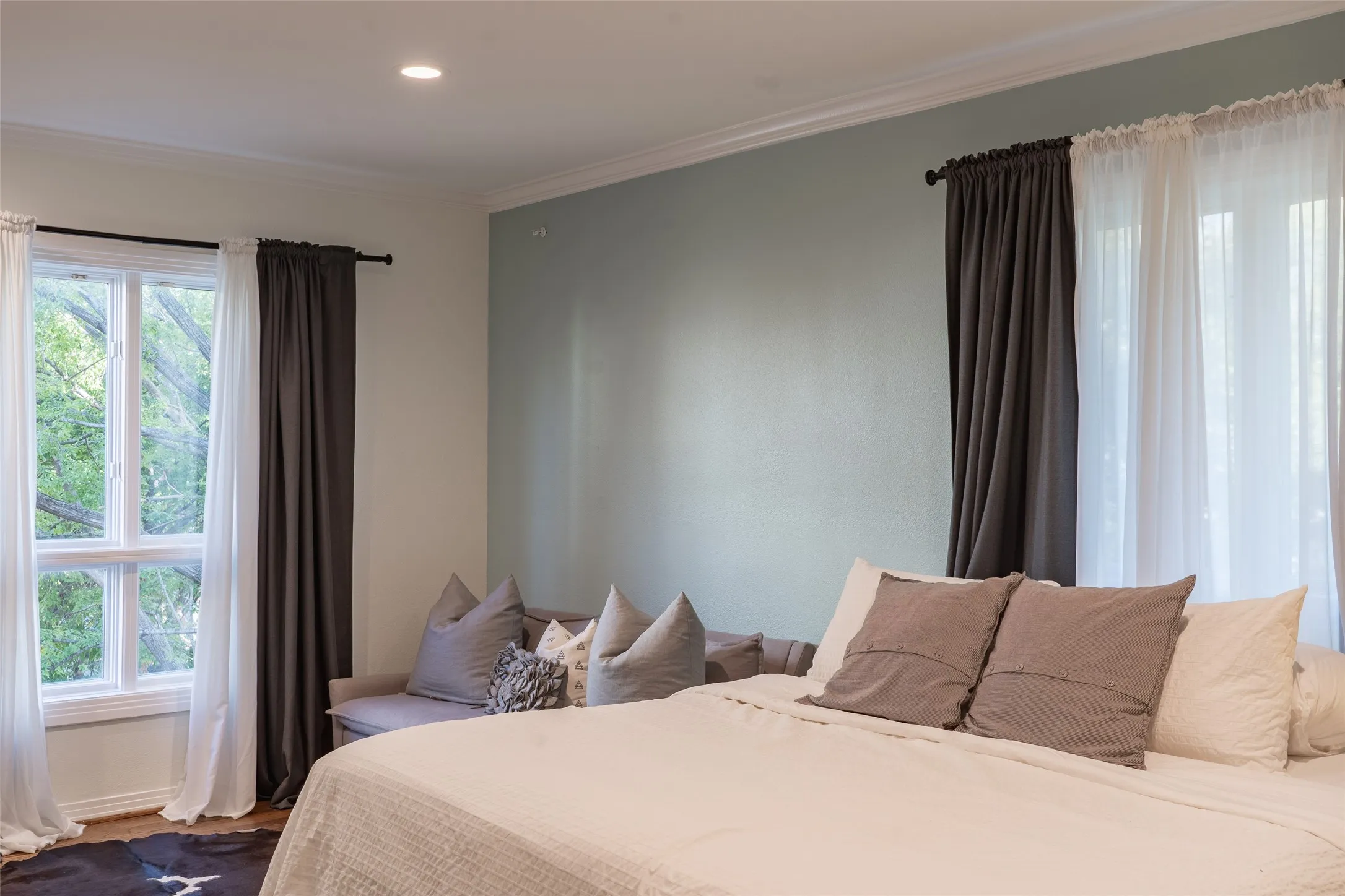 Recessed ceiling lighting illuminates a room featuring a distinct accent wall and crown molding