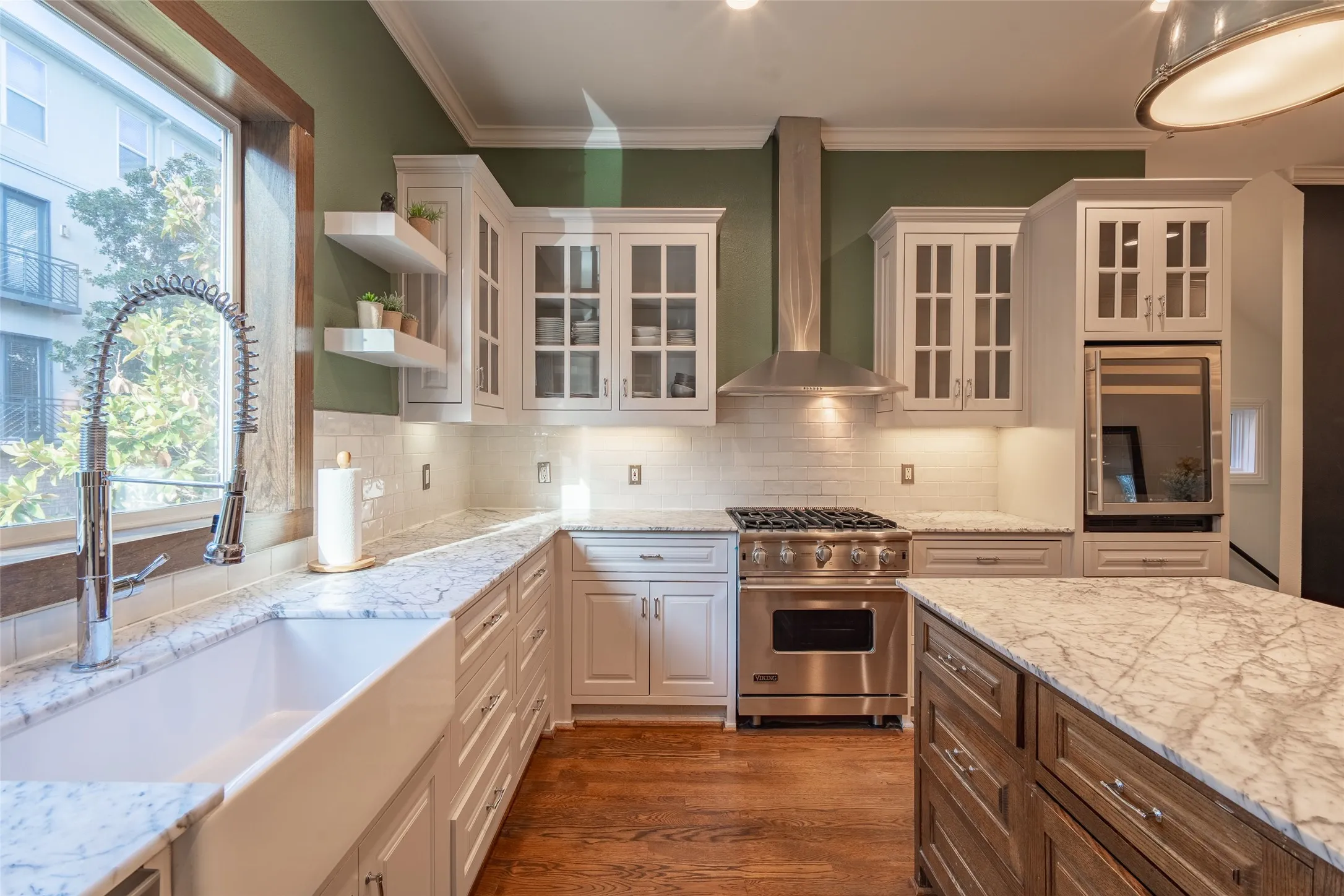 Gourmet kitchen featuring white cabinetry, professional-grade range with stainless steel hood, built-in wall oven, farmhouse sink, and stone countertops