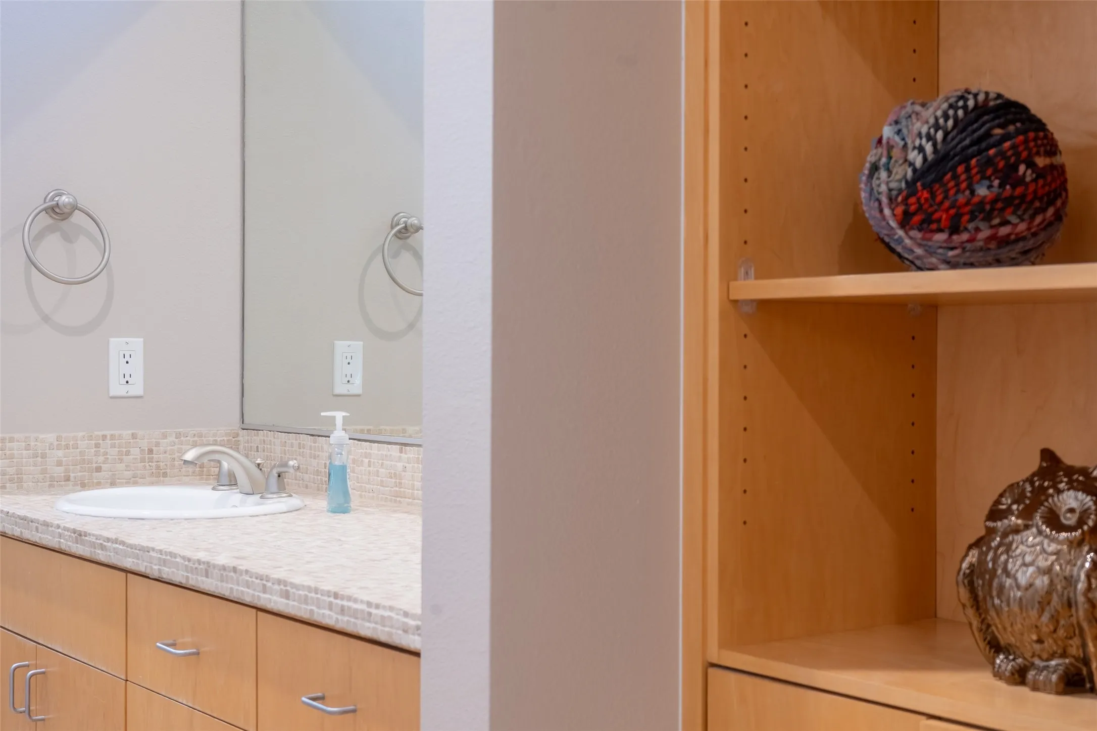 Bathroom vanity with a mosaic tile backsplash, integrated sink, and brushed nickel faucet