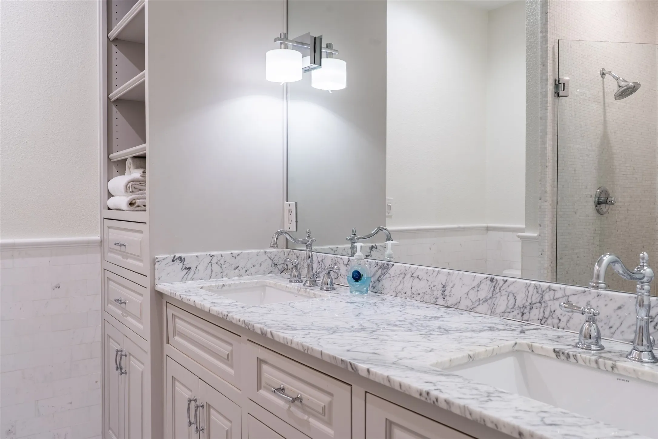 Dual vanity with undermount sinks, stone countertops, chrome fixtures, and integrated storage cabinetry