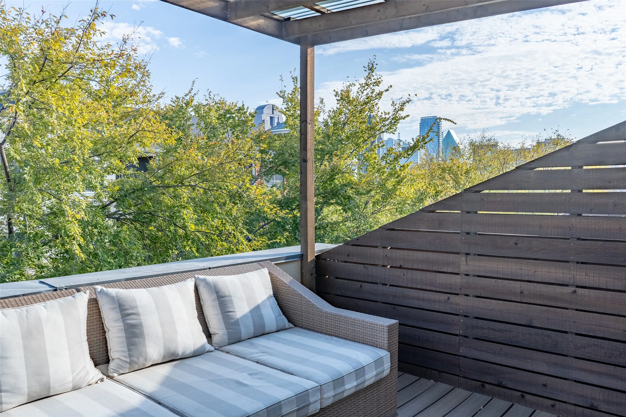 Rooftop deck featuring wood-finish decking, a slatted privacy wall, and a wooden pergola structure