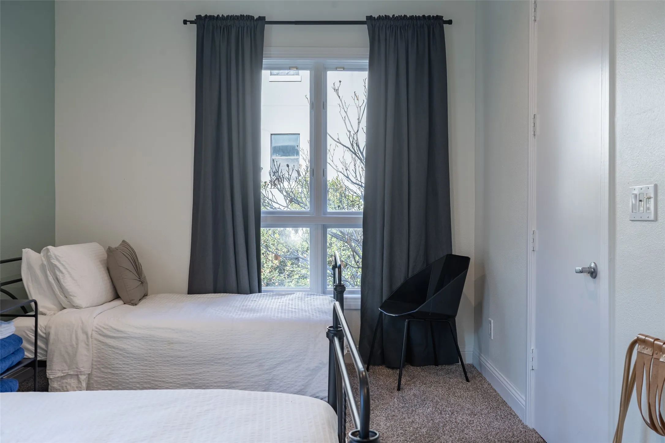 Windowed room featuring textured carpeting, a white interior door, and a multi-pane window with dark drapery
