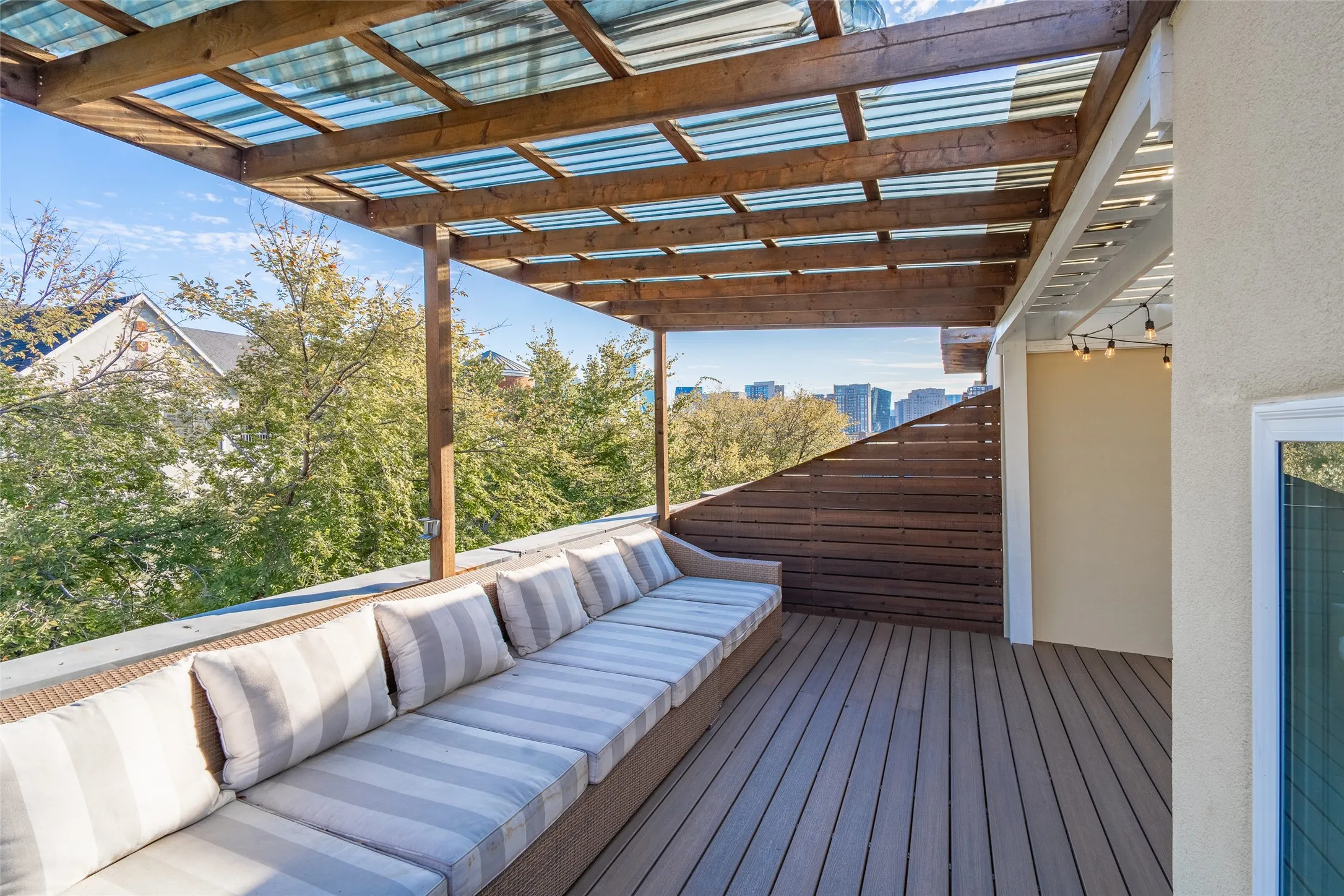 Rooftop deck featuring a wood-finish pergola with a translucent corrugated roof, composite decking, and a built-in bench