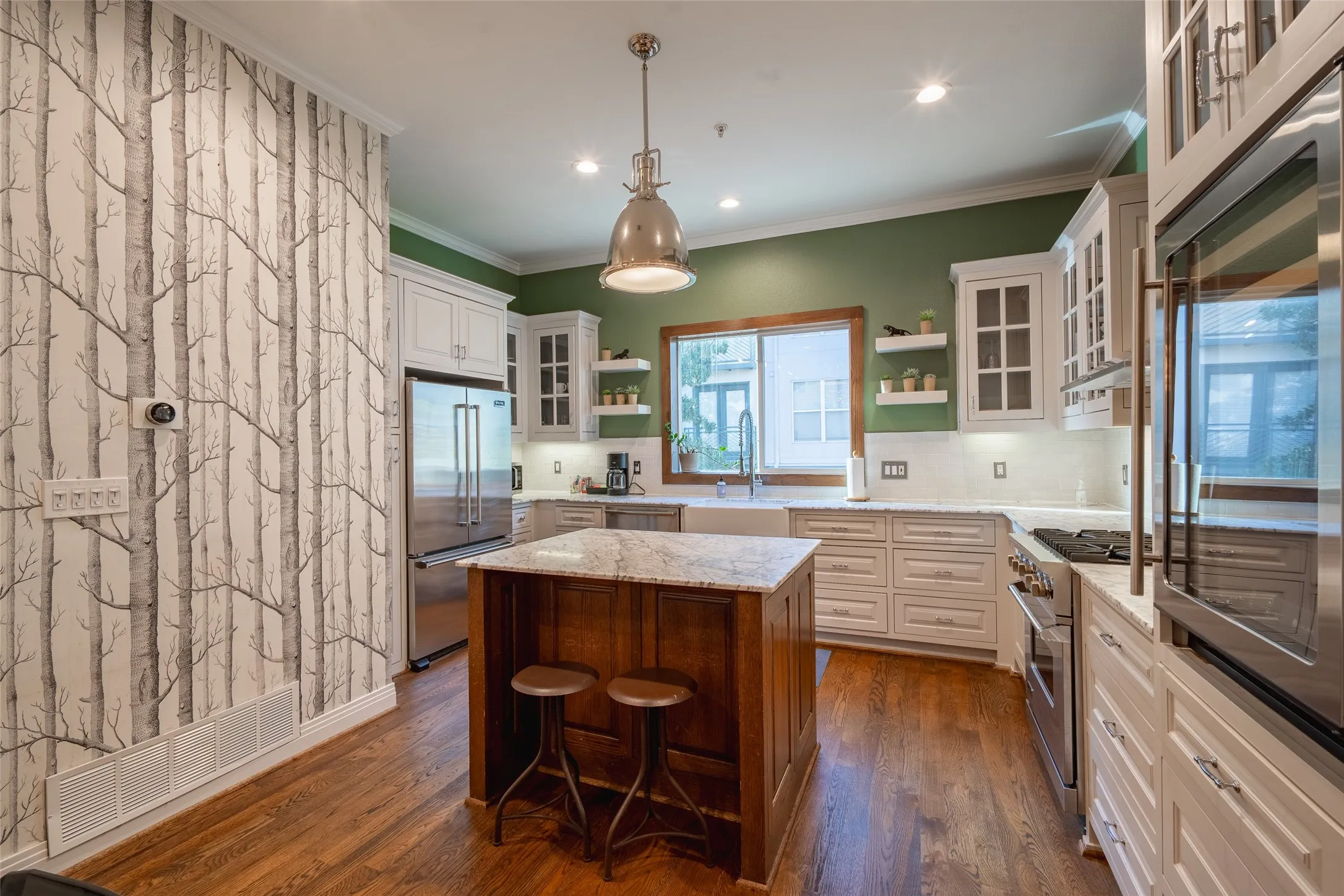 Kitchen featuring a central island with a stone countertop, white shaker-style cabinetry, stainless steel appliances, hardwood flooring, and a farmhouse sink