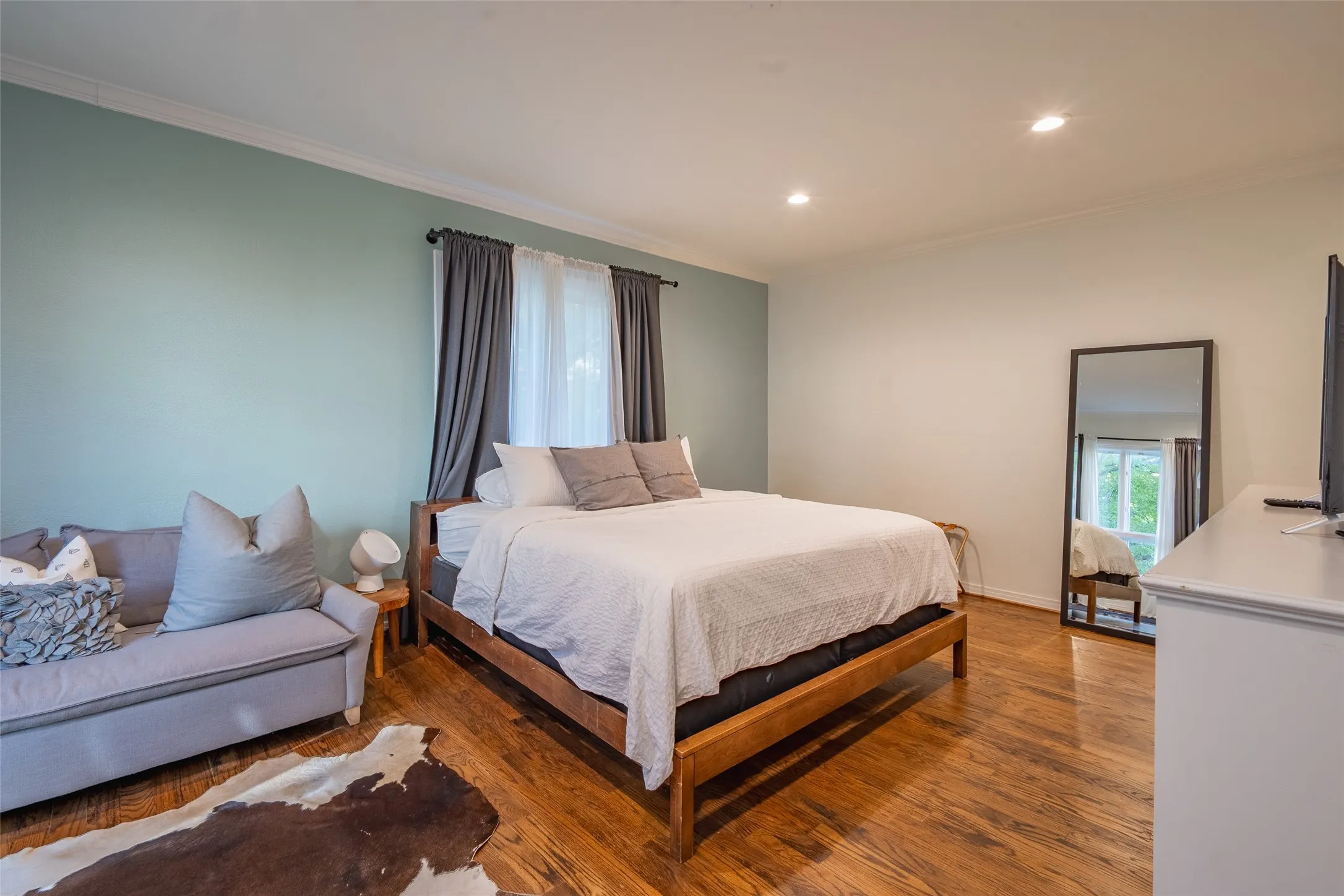 Spacious room featuring wood-finish flooring, recessed lighting, and crown molding