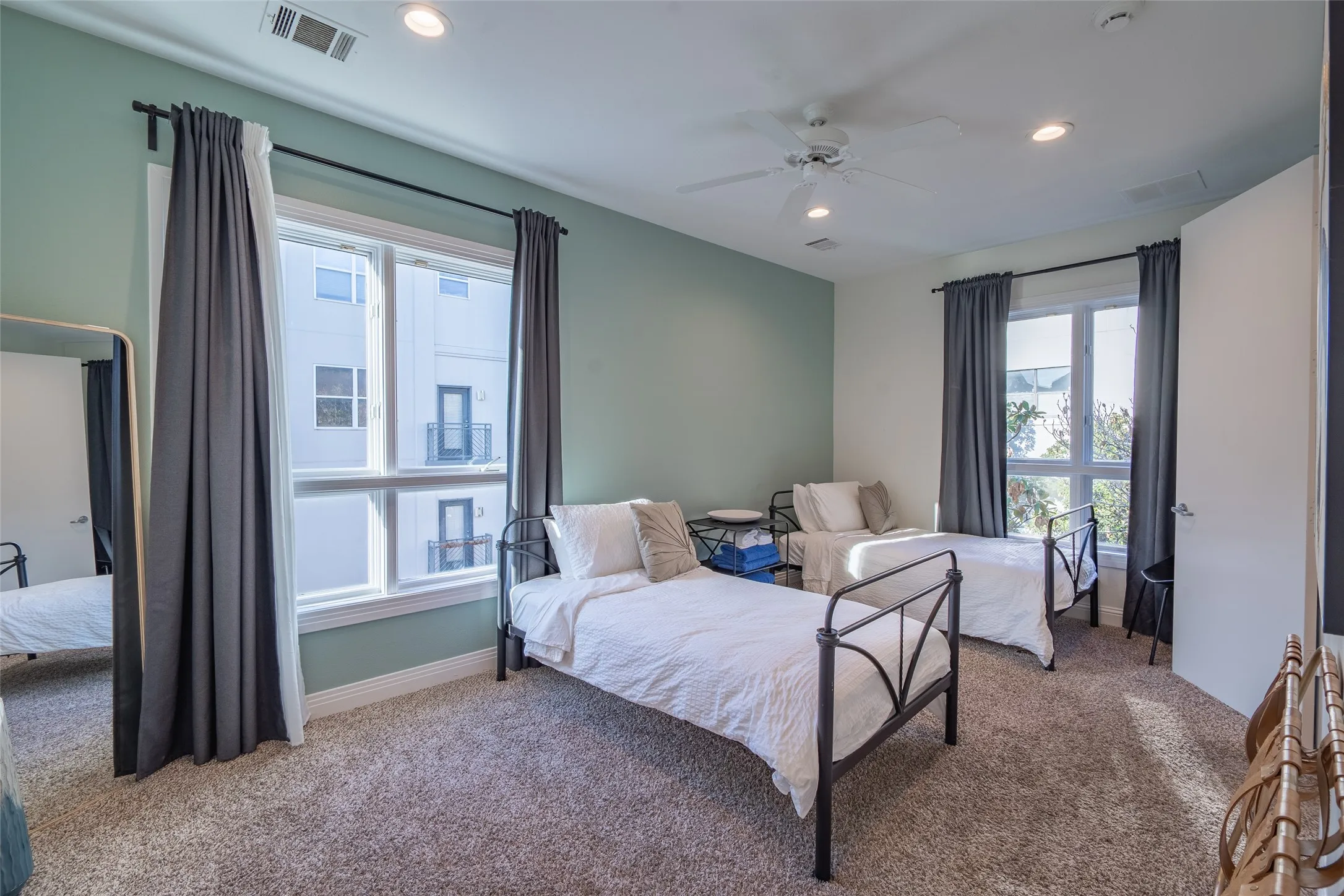 Carpeted room featuring dual windows with dark drapery, a ceiling fan, and recessed lighting