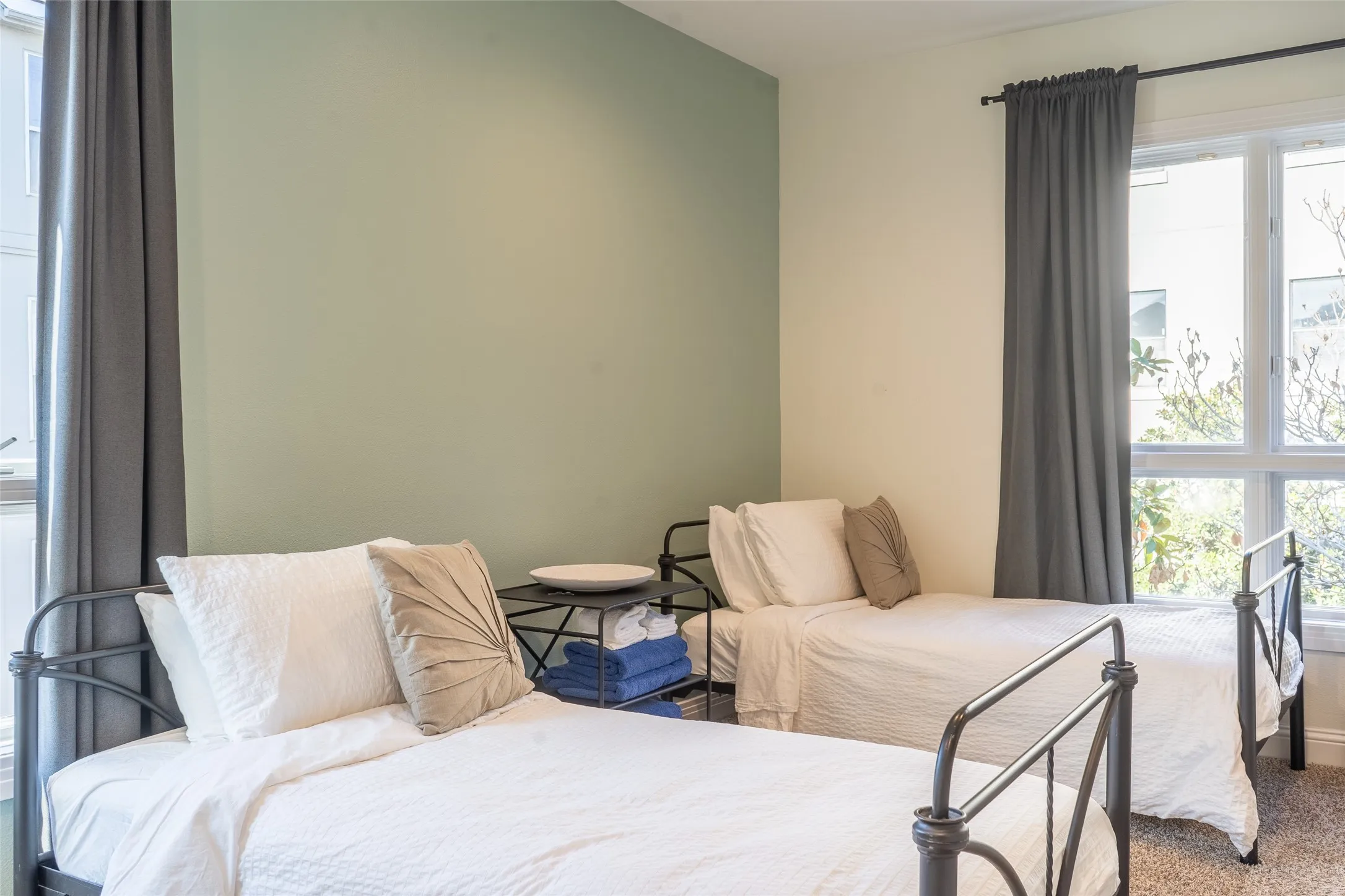 Room featuring a two-tone wall with a light green accent, a large window with dark drapes, and textured carpeting