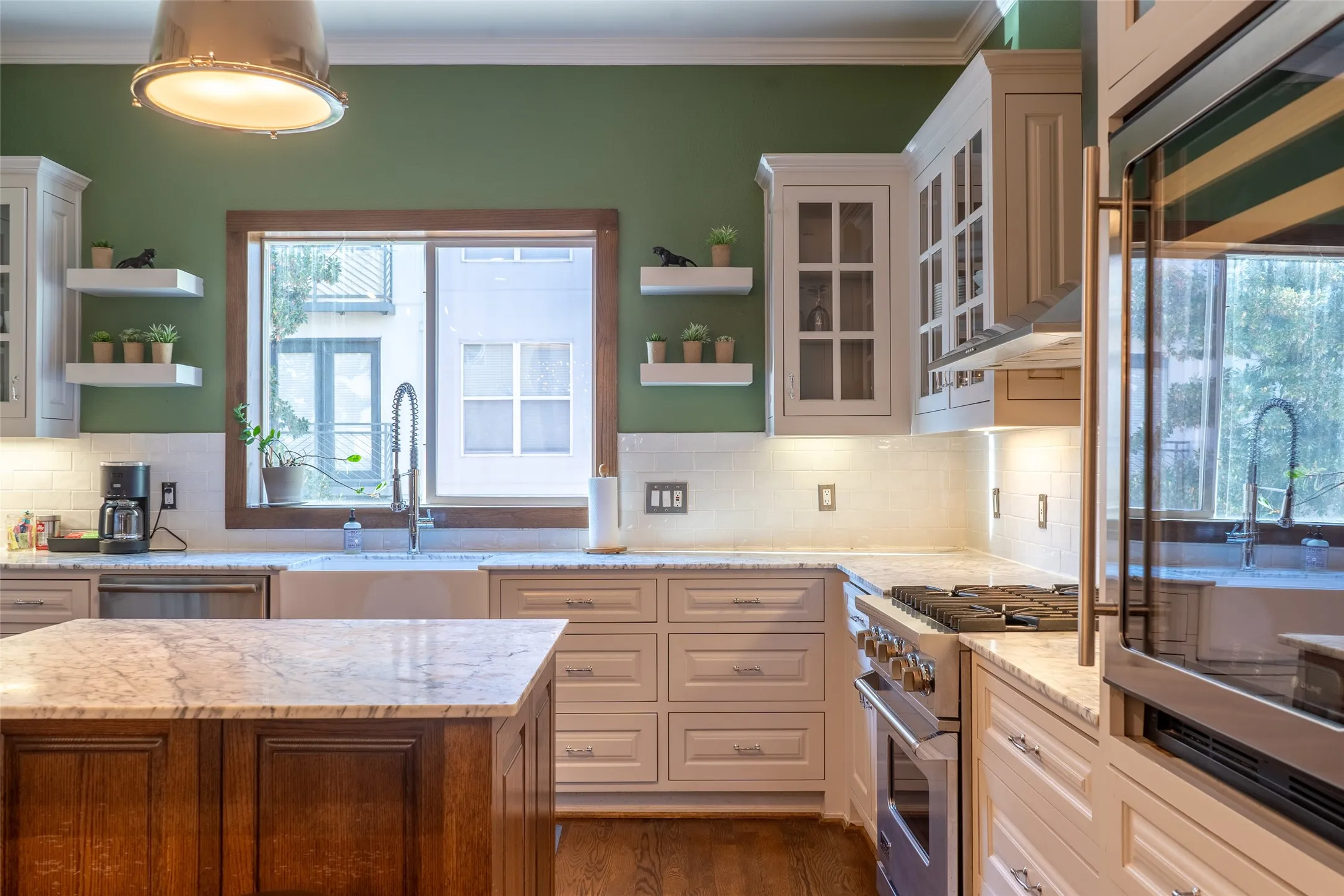 Kitchen featuring a wood-finish island with stone countertops, a large window with a deep sill, a farmhouse sink with a gooseneck faucet, white subway tile backsplash, and stainless steel appliances