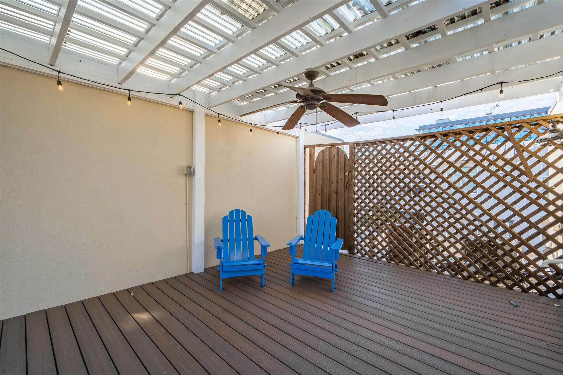 Outdoor patio featuring a slatted pergola, plank flooring, a ceiling fan, and string lighting