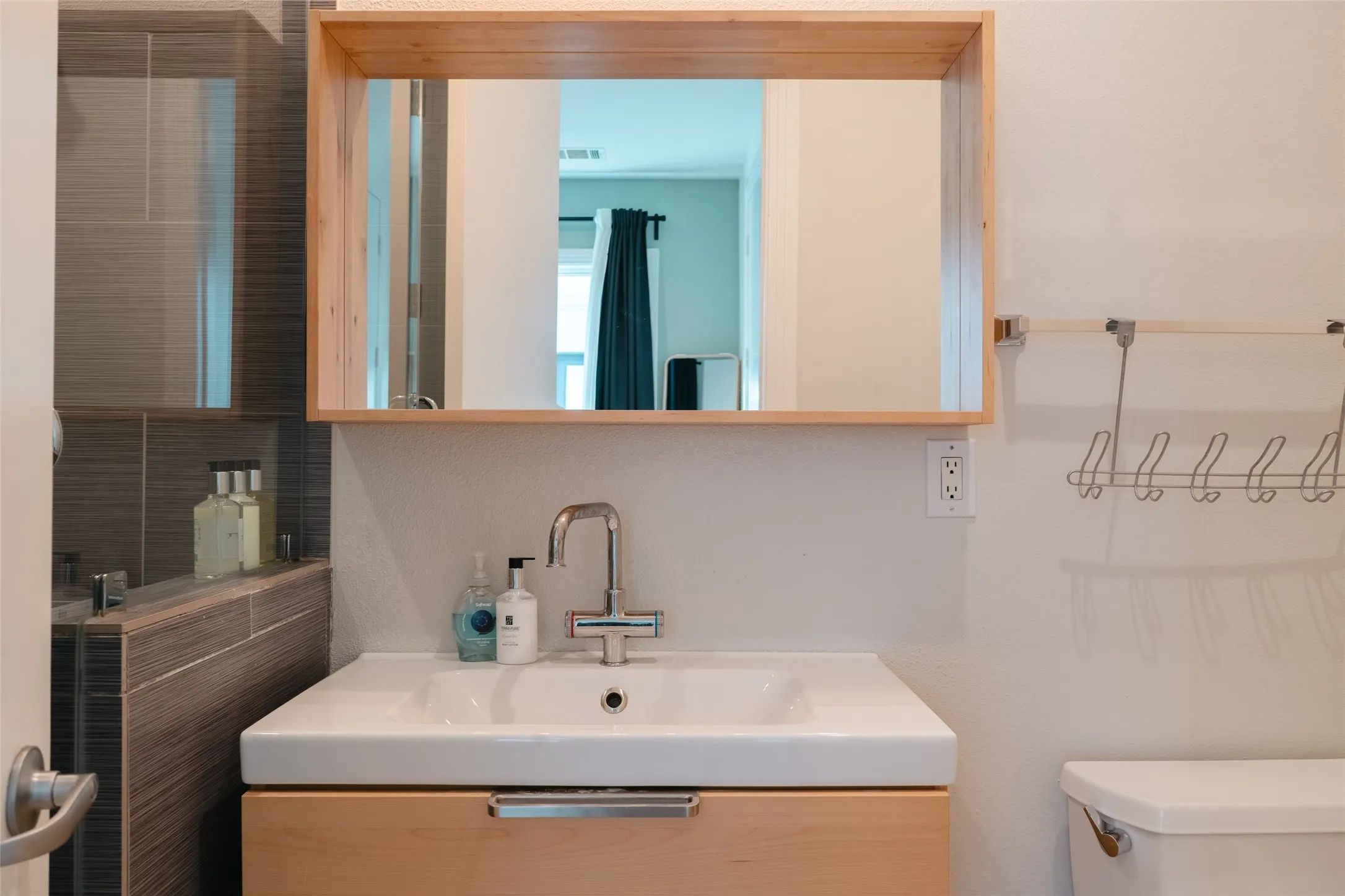 Bathroom vanity featuring an integrated rectangular sink, chrome faucet, and light wood-finish cabinetry