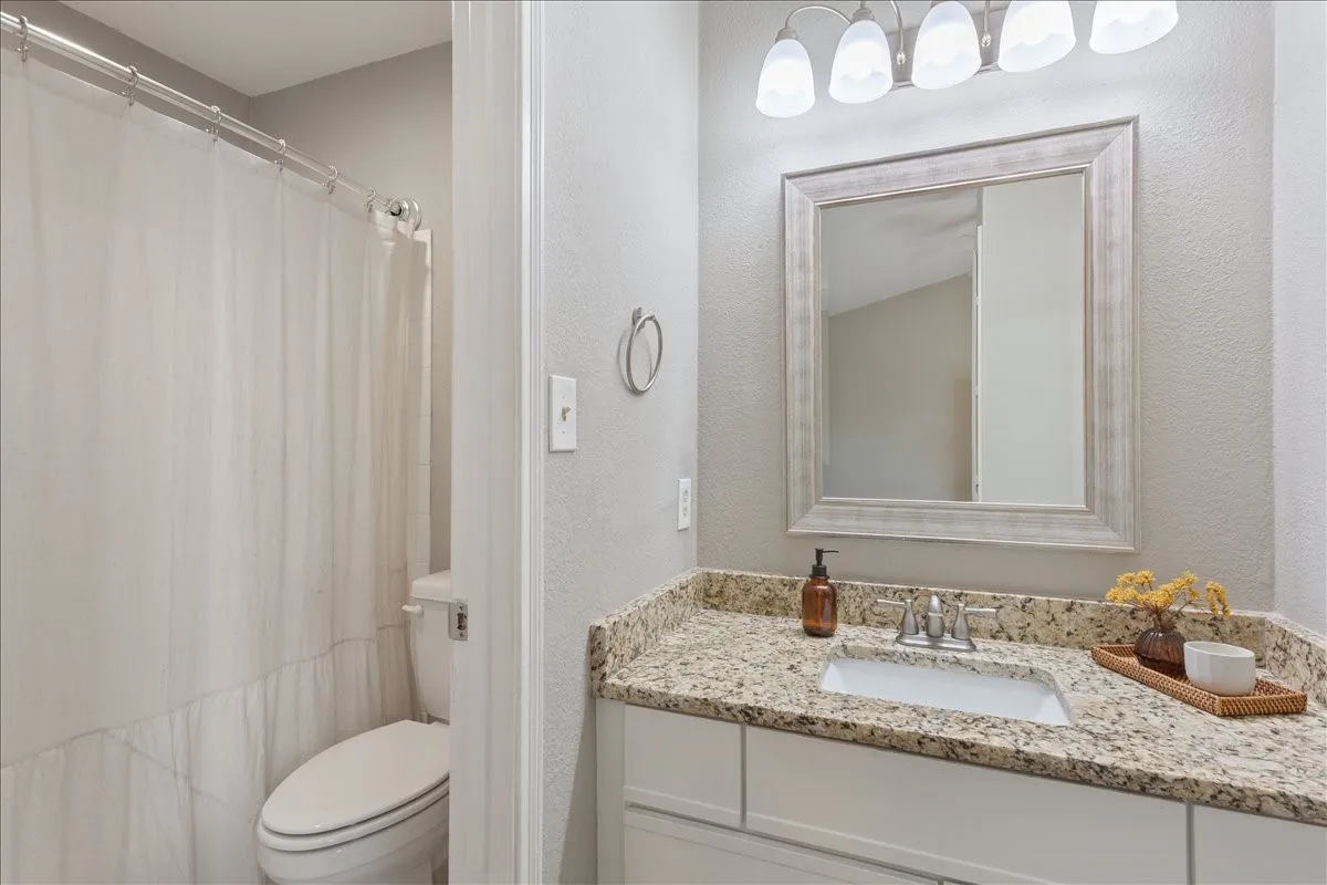Updated primary bath with granite countertops, modern fixtures, and refreshed finishes.