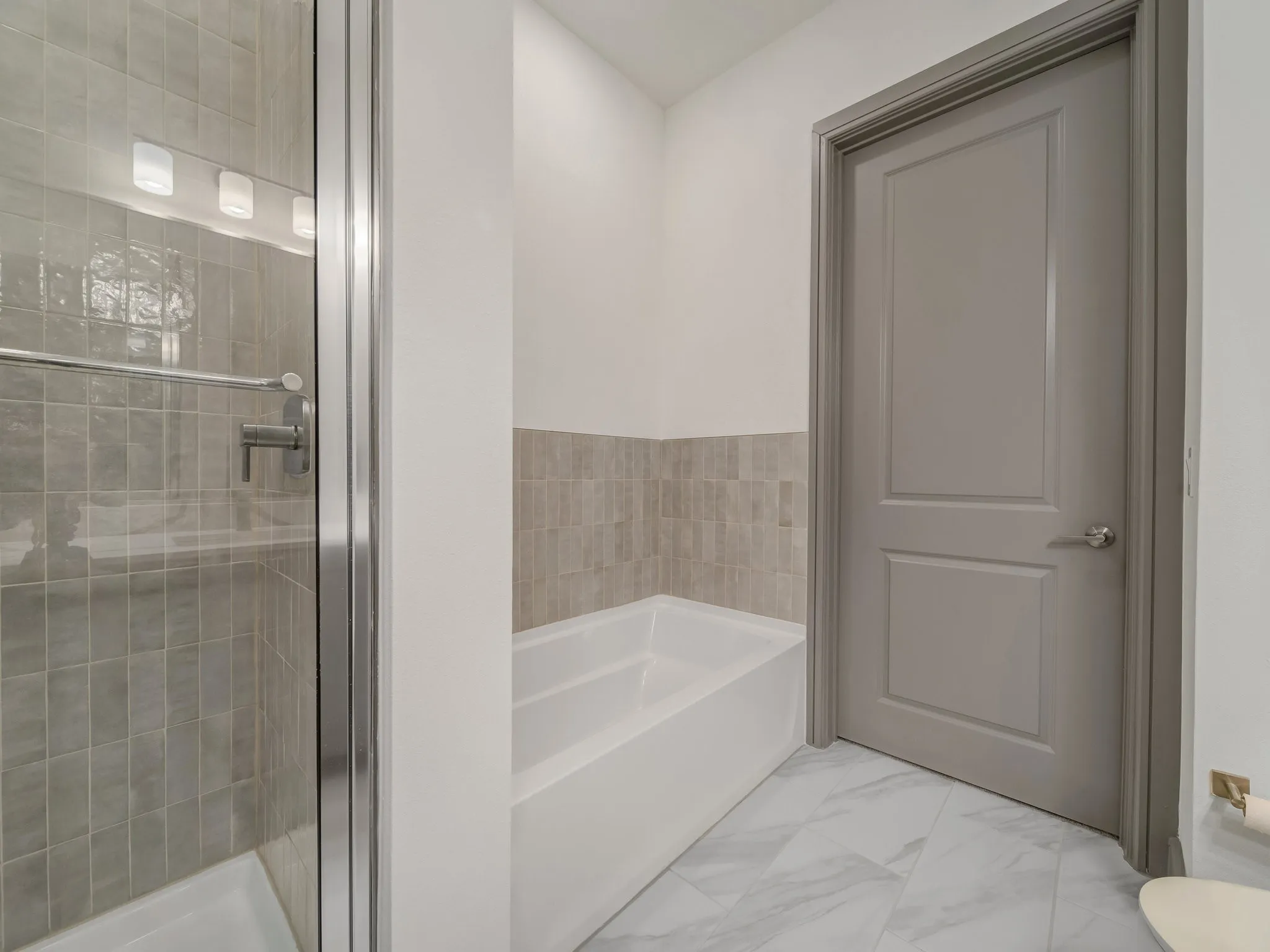 Bathroom featuring a glass-enclosed shower, a built-in bathtub, and a paneled door