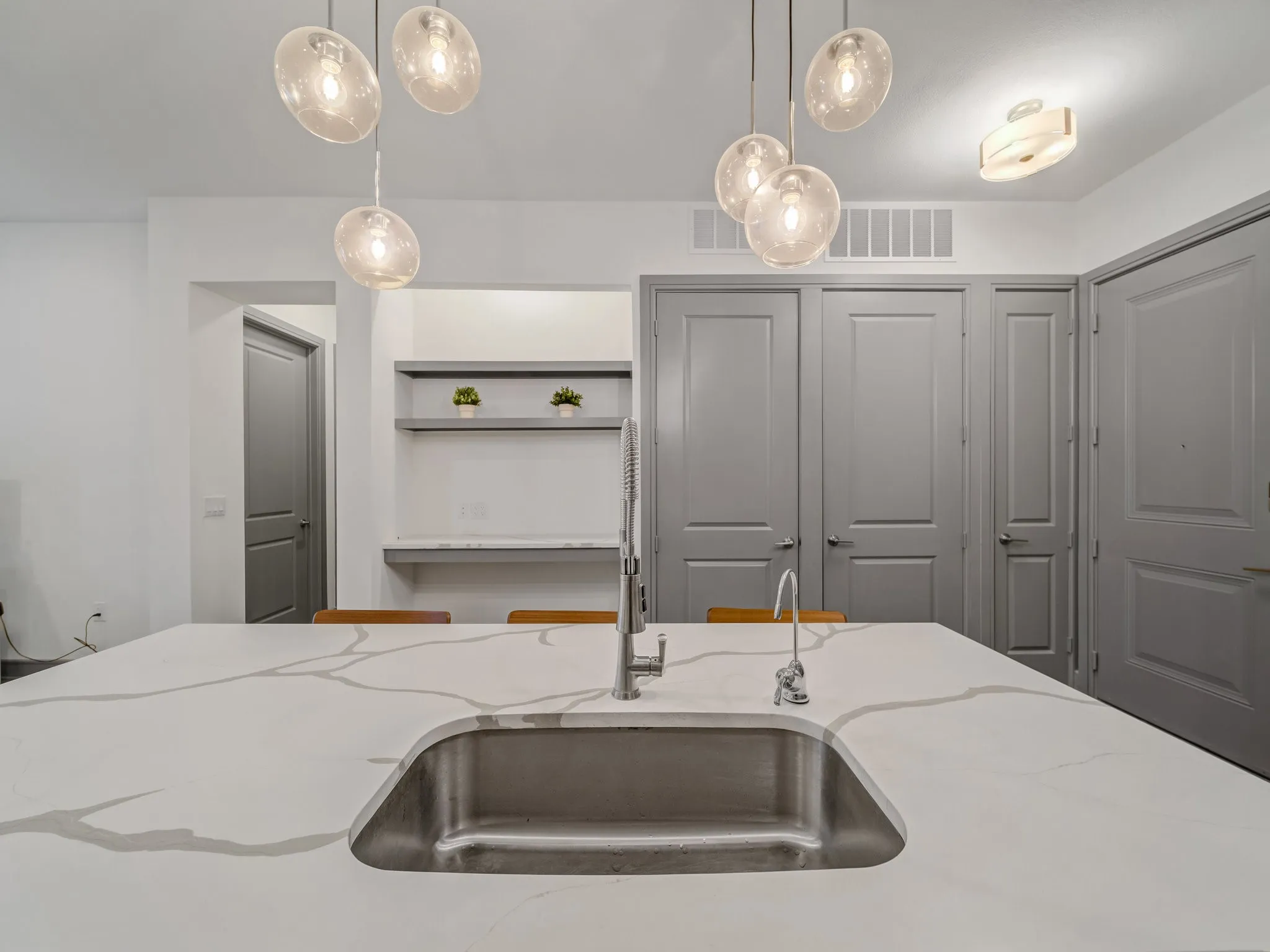 Expansive island with integrated stainless steel sink and modern faucet, featuring a white countertop with grey veining