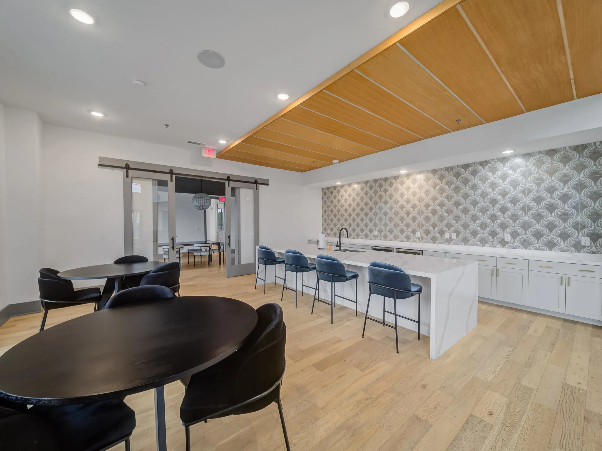 Open-concept lounge area featuring wood-finish flooring, a contemporary accent wall, and recessed lighting