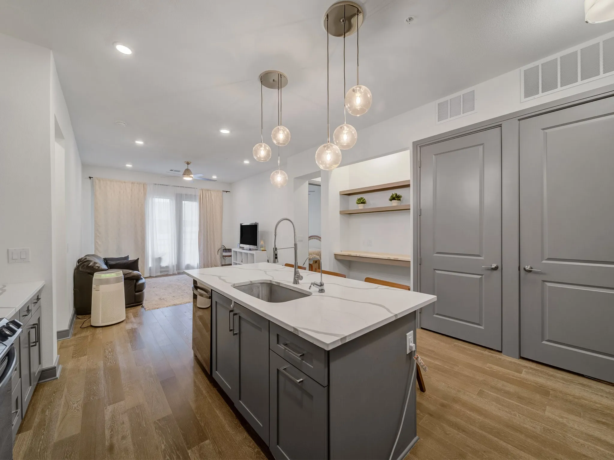 Modern kitchen island featuring a stainless steel sink, gooseneck faucet, and pendant lighting