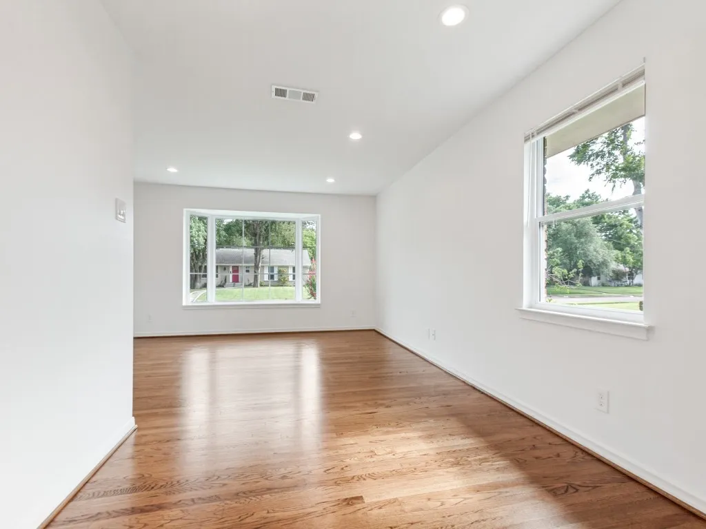 Spacious room featuring wood-finish flooring, recessed lighting, and a prominent bay window