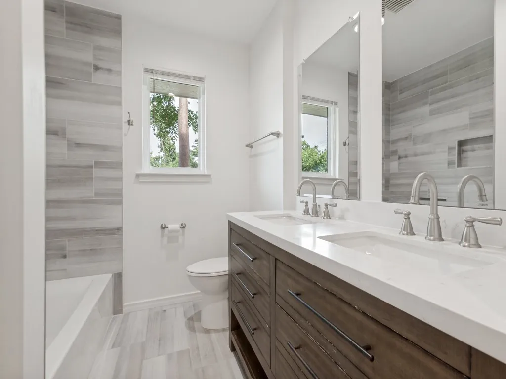 Bathroom featuring a dark wood-finish dual vanity with white countertops, undermount sinks, and brushed nickel fixtures